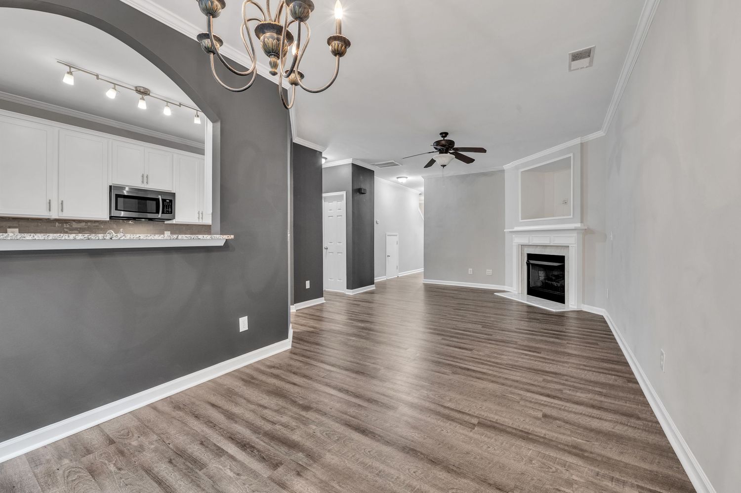 Open concept living space with modern lighting fixtures, gray accent walls, and engineered hardwood flooring.
