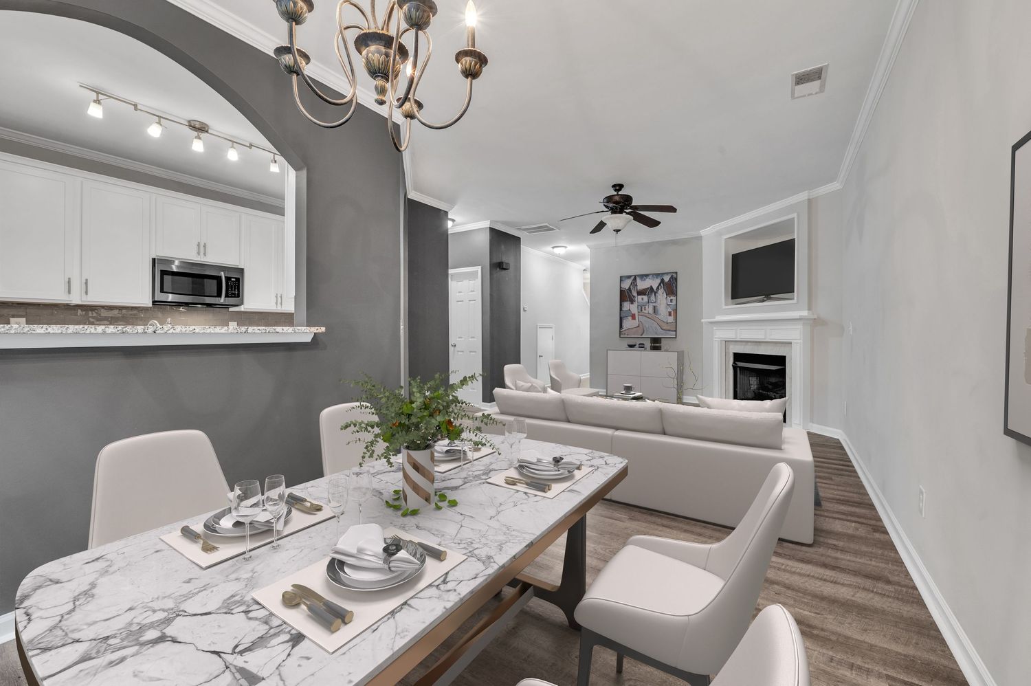 Bright kitchen and dining area with marble countertops, contemporary lighting, and white cabinetry.