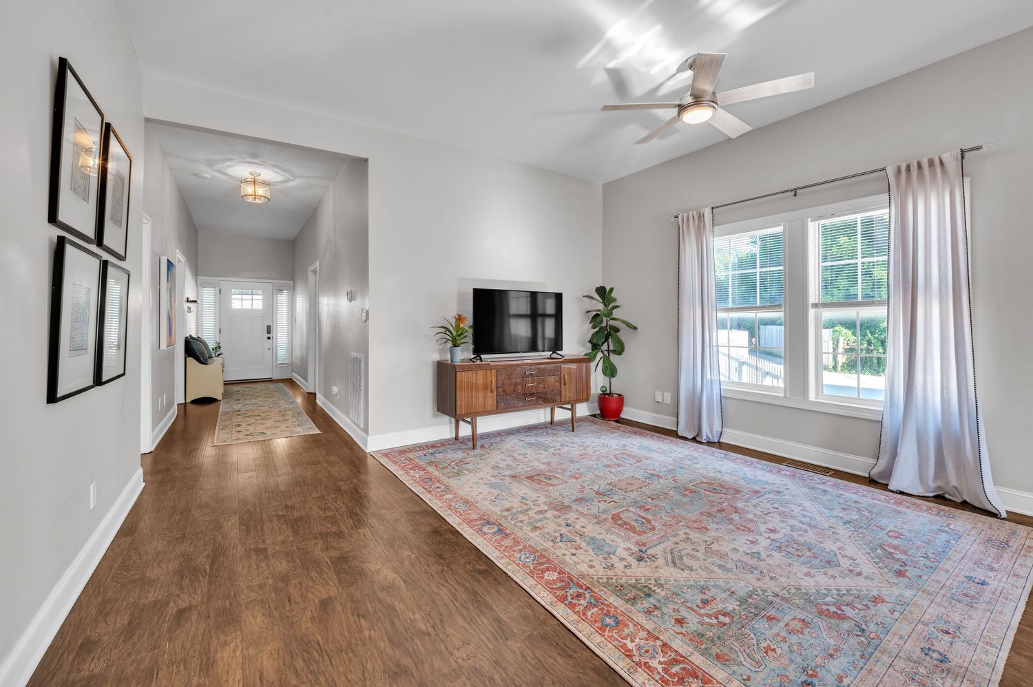 Long hallway with hardwood floors, white walls, and vintage-style oriental rug.