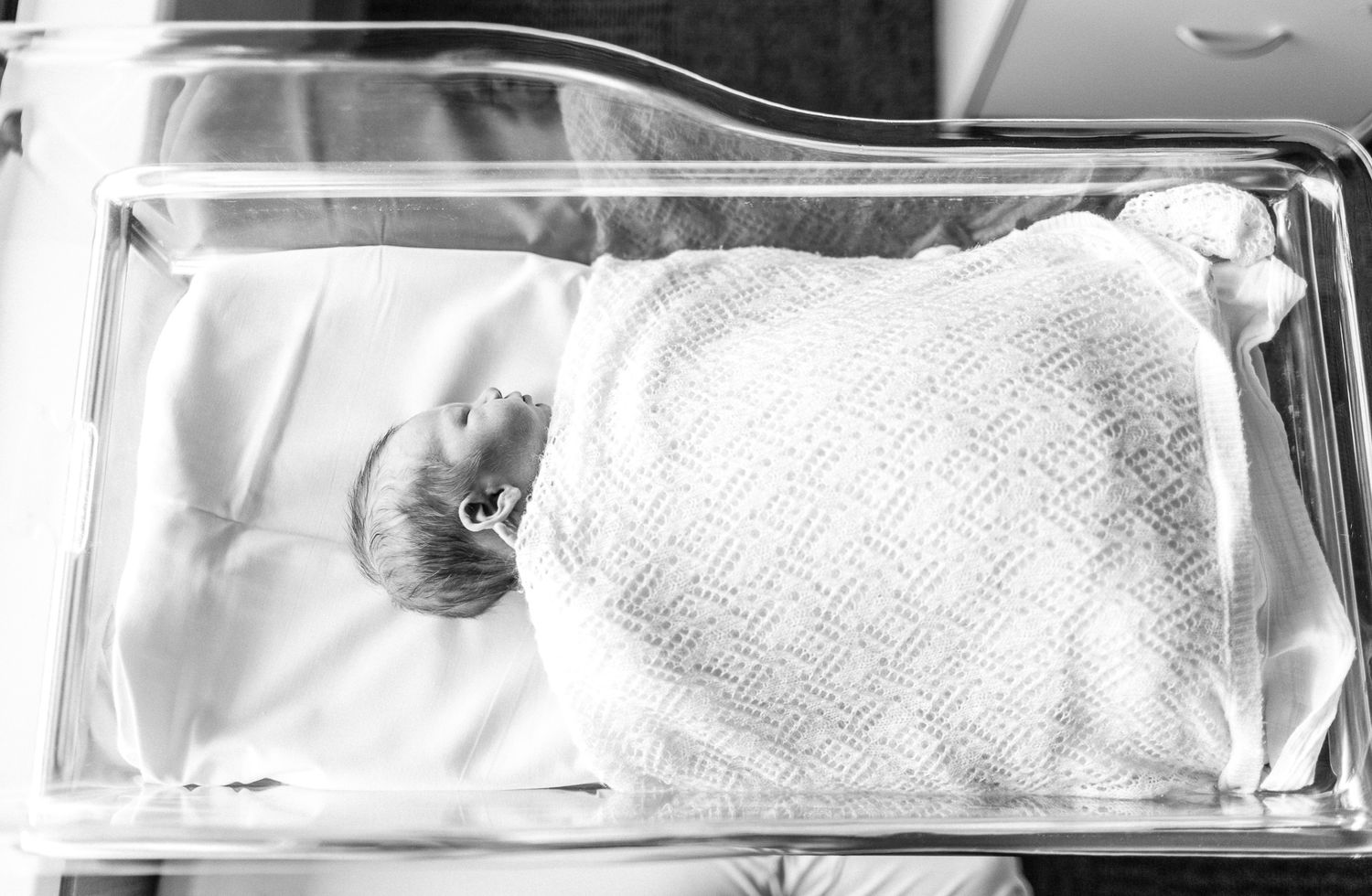 Newborn baby sleeping peacefully in a hospital bassinet.