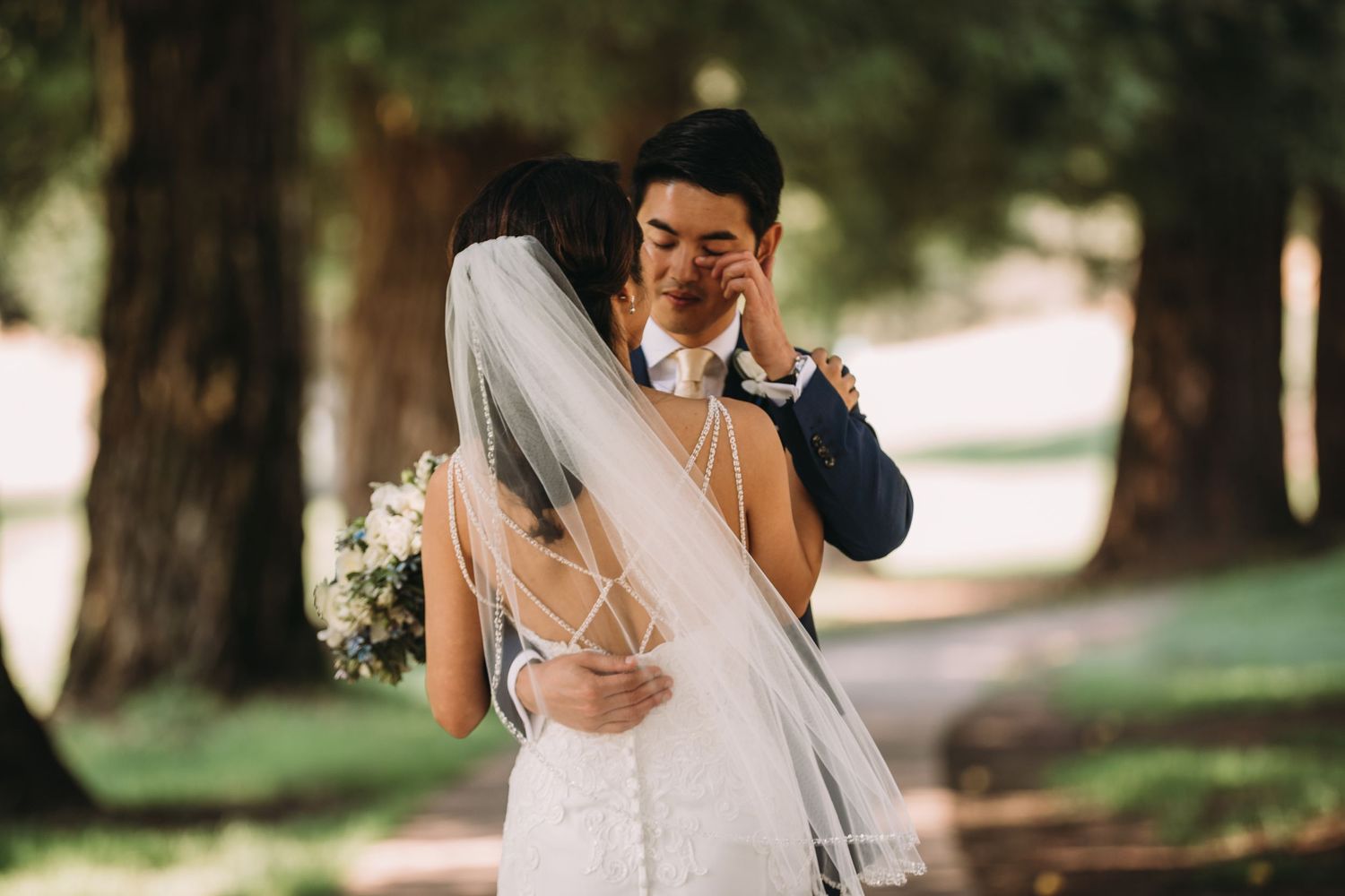 A tender wedding moment captured as a couple embraces during their first look in a sunlit garden.
