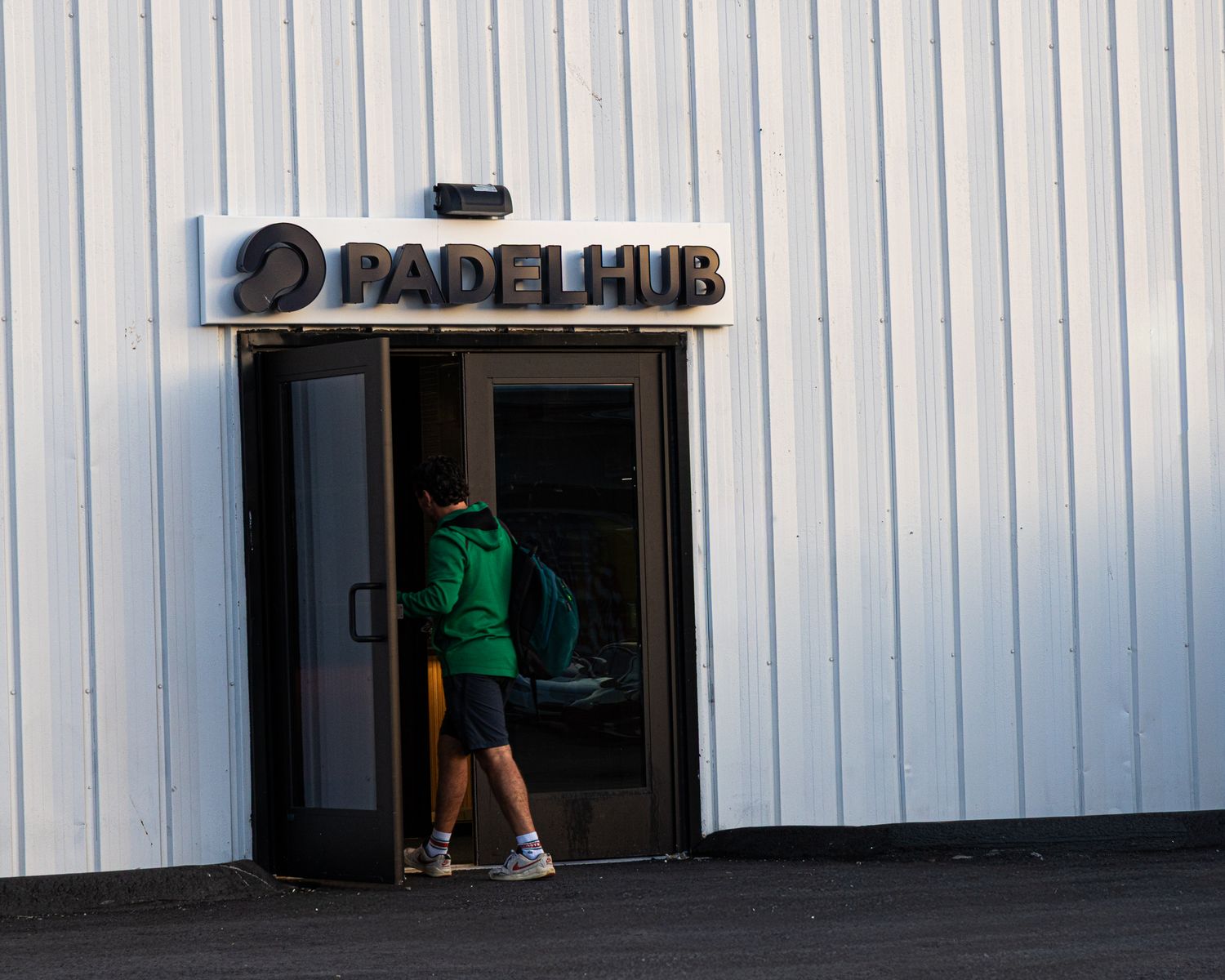 Child entering PadelHub sports facility through glass doors at the main entrance.