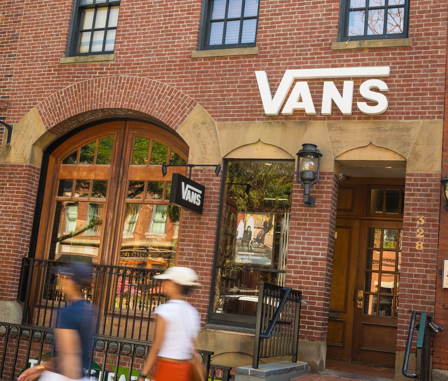 Vans shoe store brick exterior with shoppers walking past in an urban shopping district.