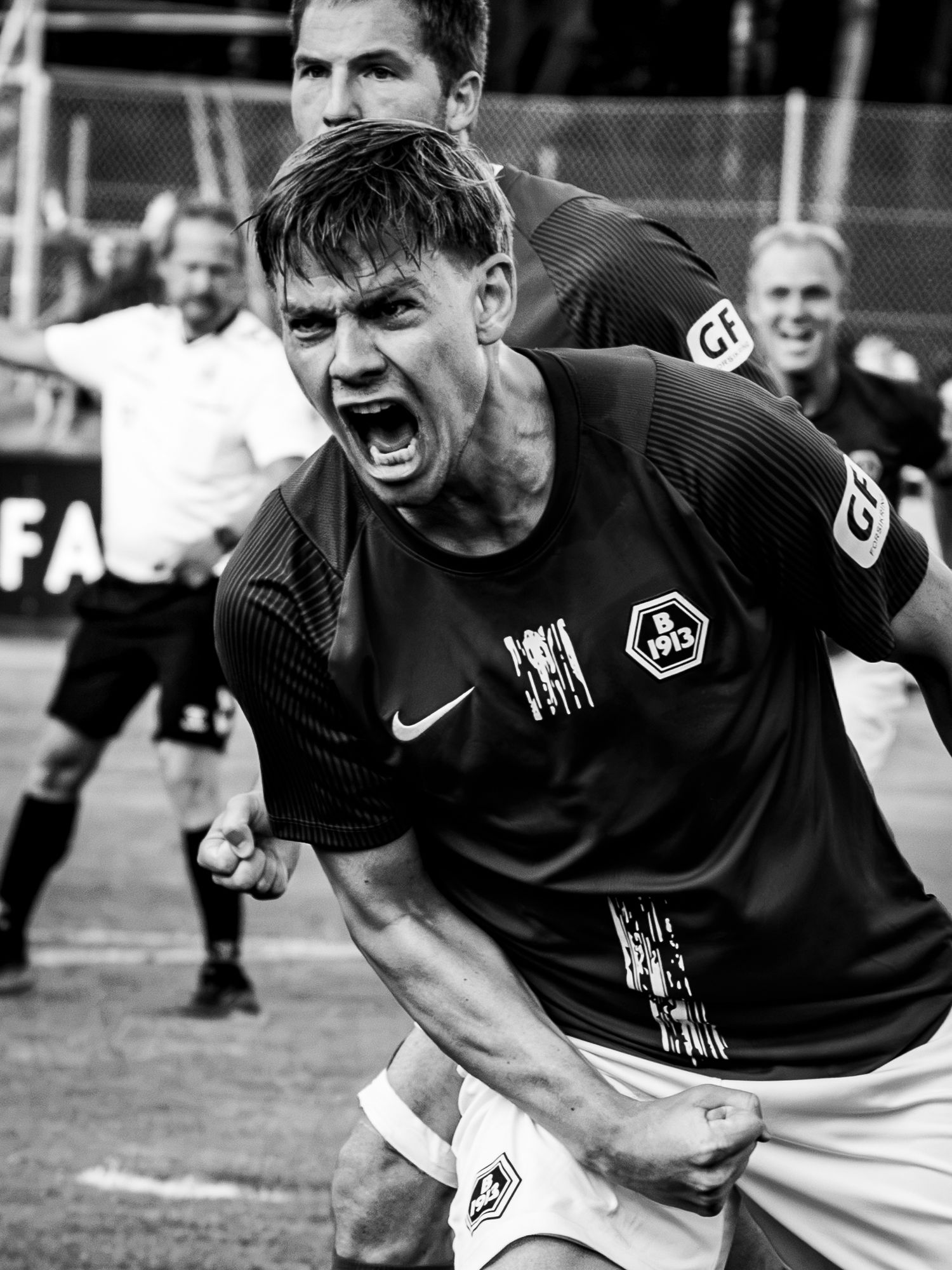 Black and white photo of a soccer player celebrating a goal, screaming with fist clenched in Nike jersey.