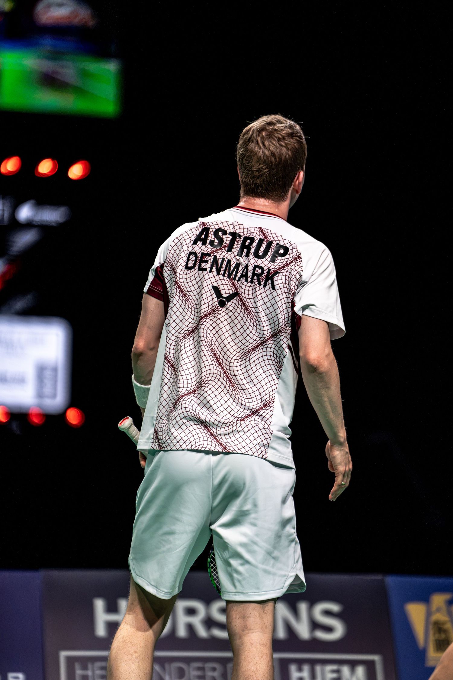 Badminton player Astrup from Denmark seen from behind wearing white Victor jersey at BWF Thomas Cup Finals in Horsens.