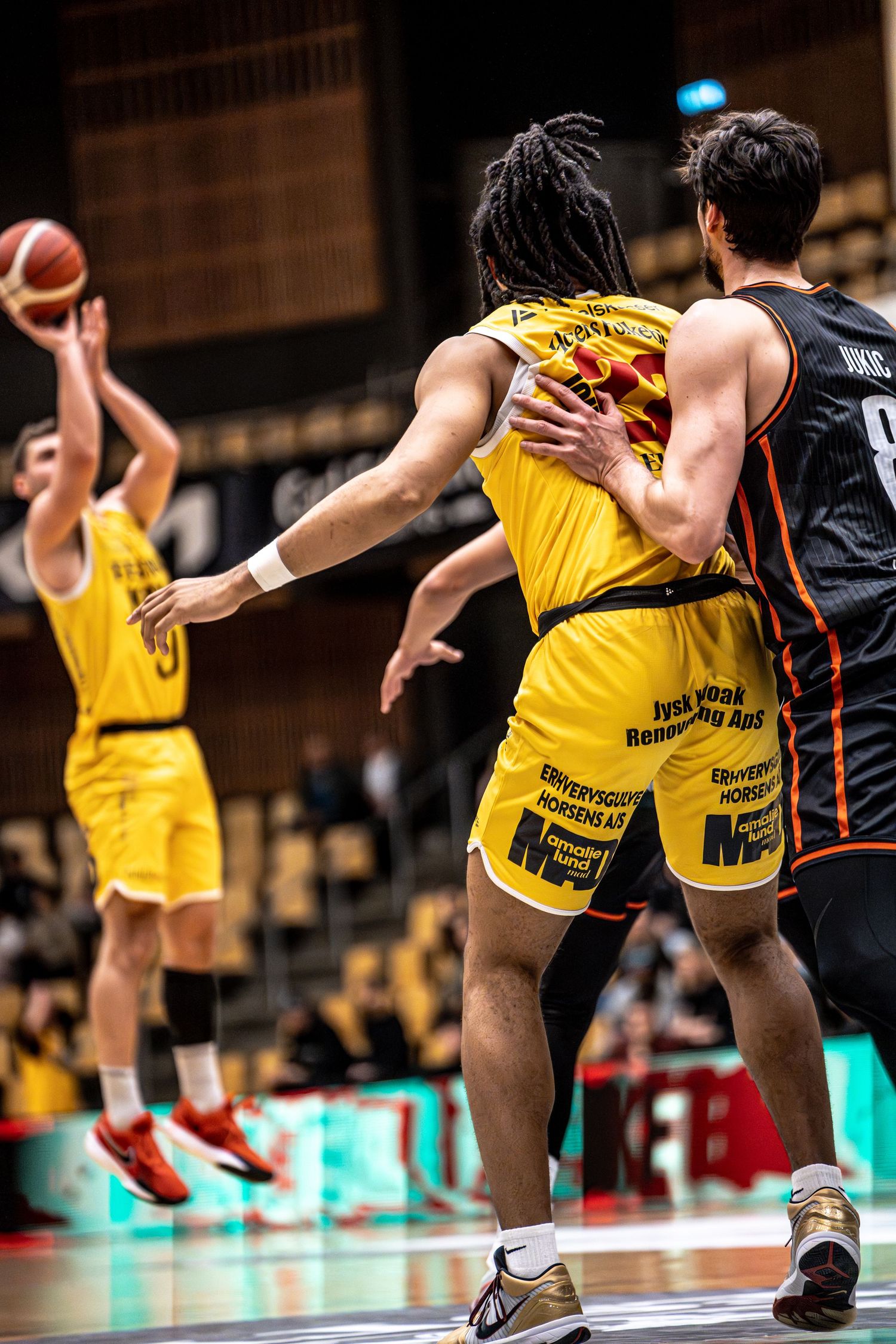 Yellow team player screens defender while teammate attempts a jump shot nearby.
