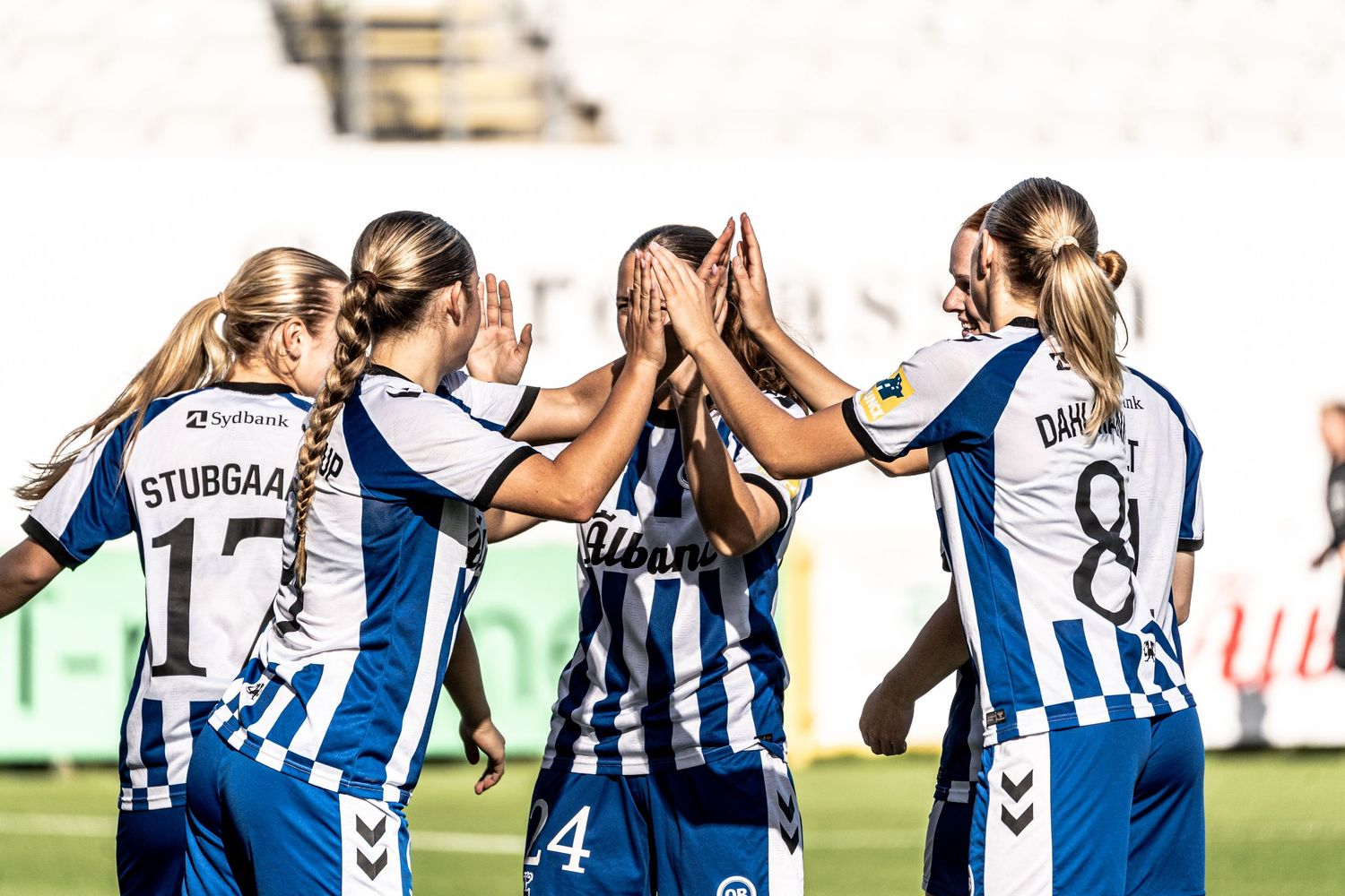 Women's football team including Stubbgaard and Dahl celebrate together with high-fives after scoring.