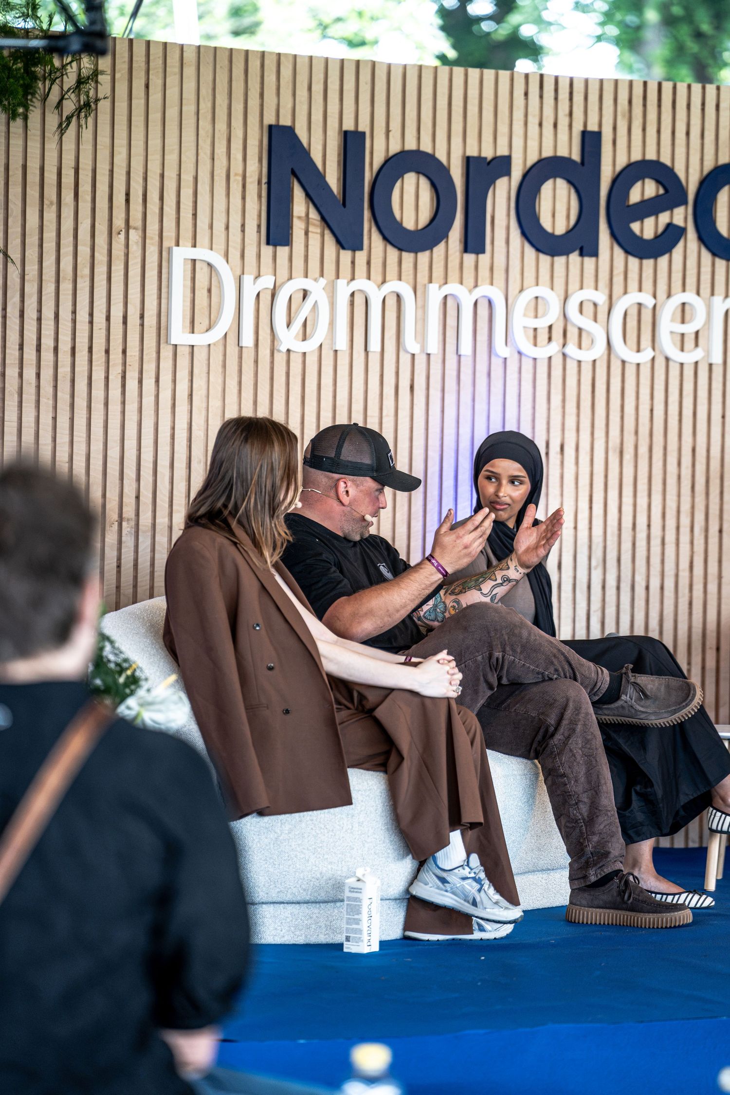 Three panelists in discussion at the Nordea Drømmescene outdoor stage during a festival event.