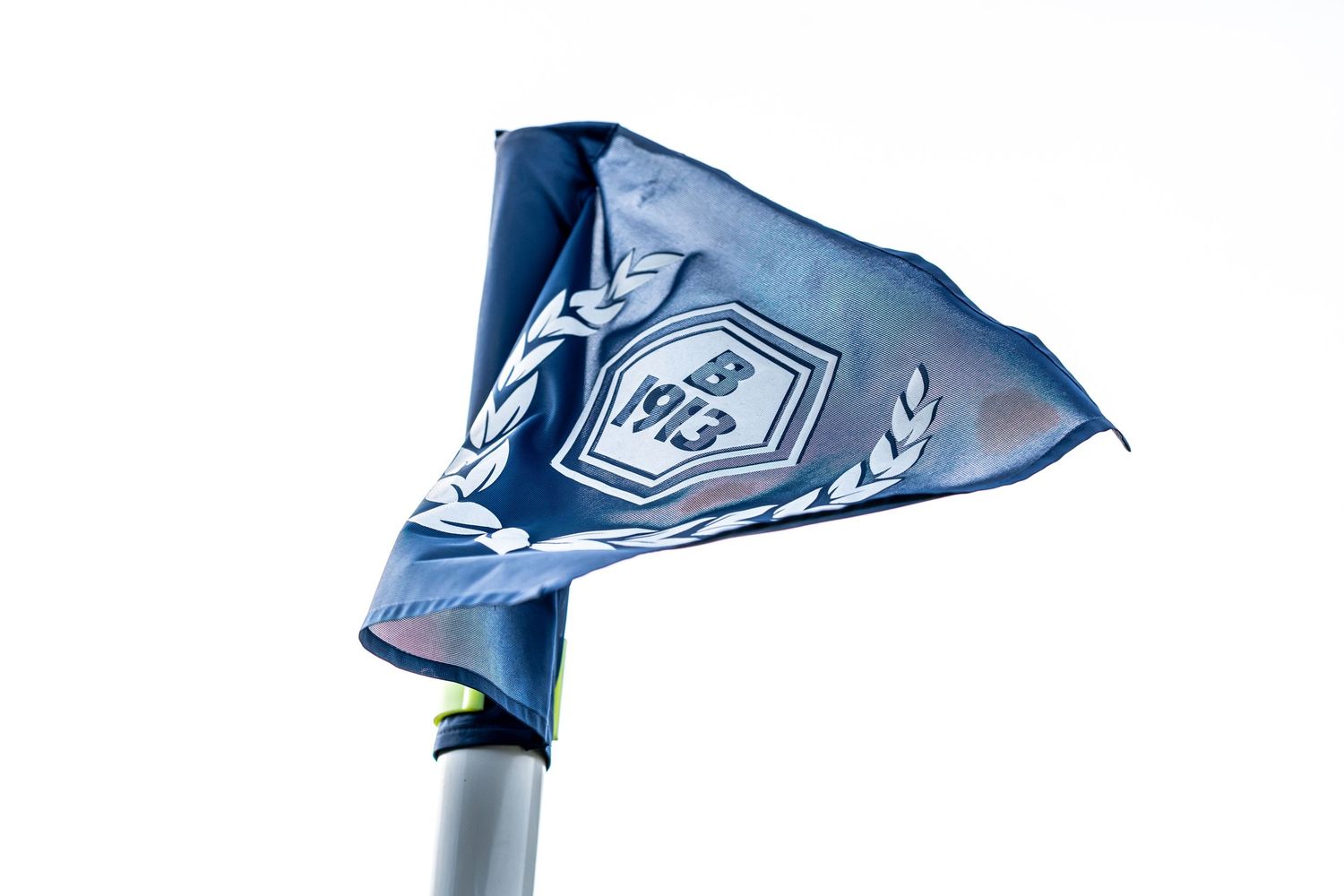 Blue corner flag with B 1913 club crest blowing in the wind against a white sky.