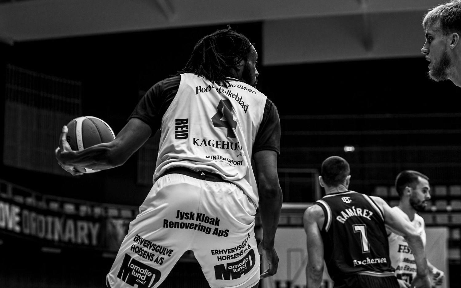 Black and white photo of basketball player number 4 holding ball during competitive game.