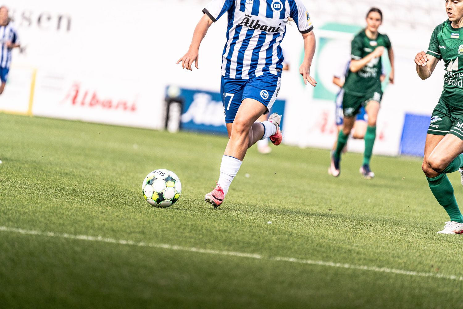 Female soccer player in blue-white number 7 jersey races with ball during a women's football match.