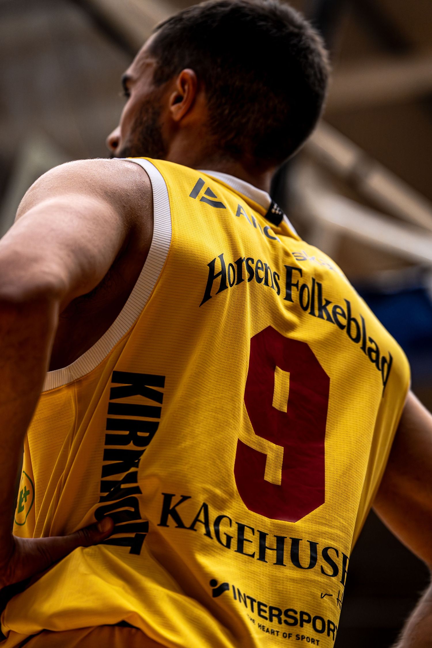 Back view of basketball player wearing yellow number 9 Horsens Folkebladet jersey.