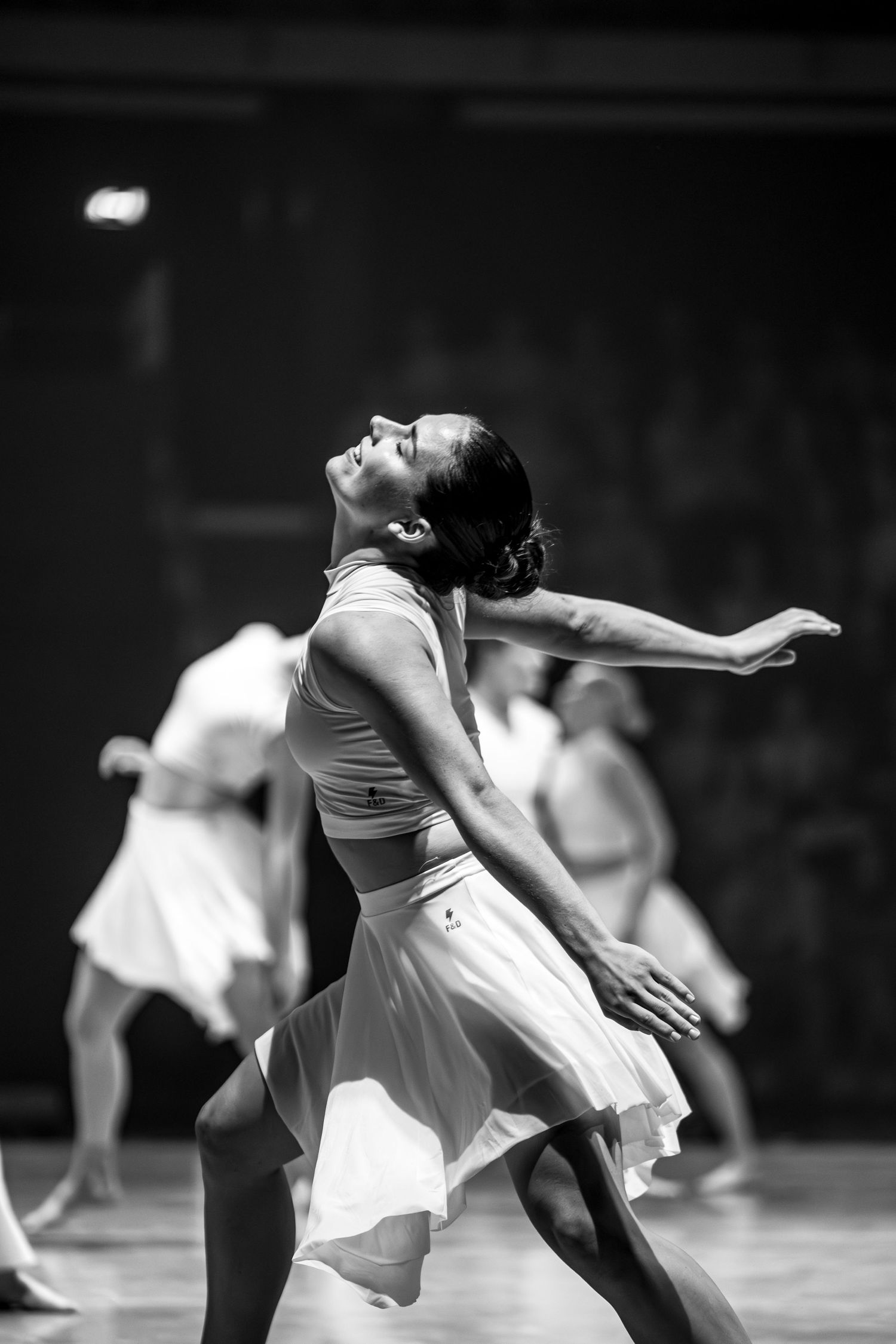 Black and white image of female contemporary dancer in white skirt performing graceful solo routine.