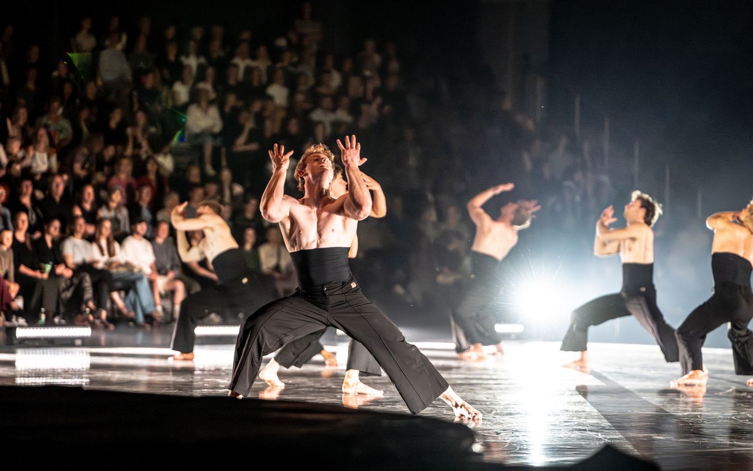 Contemporary dancers performing an energetic routine on a stage before a live audience.
