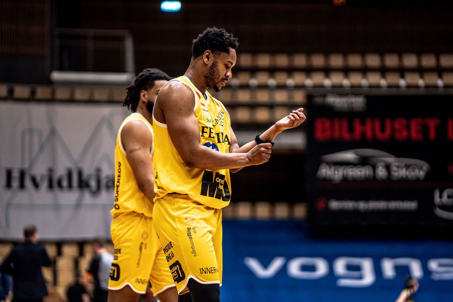 Two yellow-uniformed basketball players celebrate together on court during a professional game.