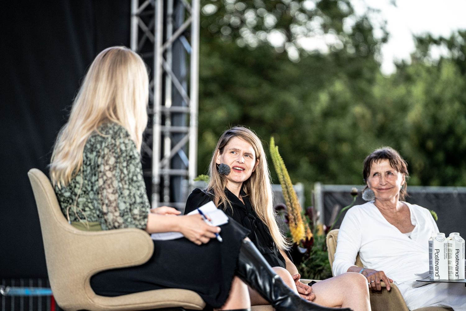 Three women seated on stage during outdoor panel discussion at summer festival event.