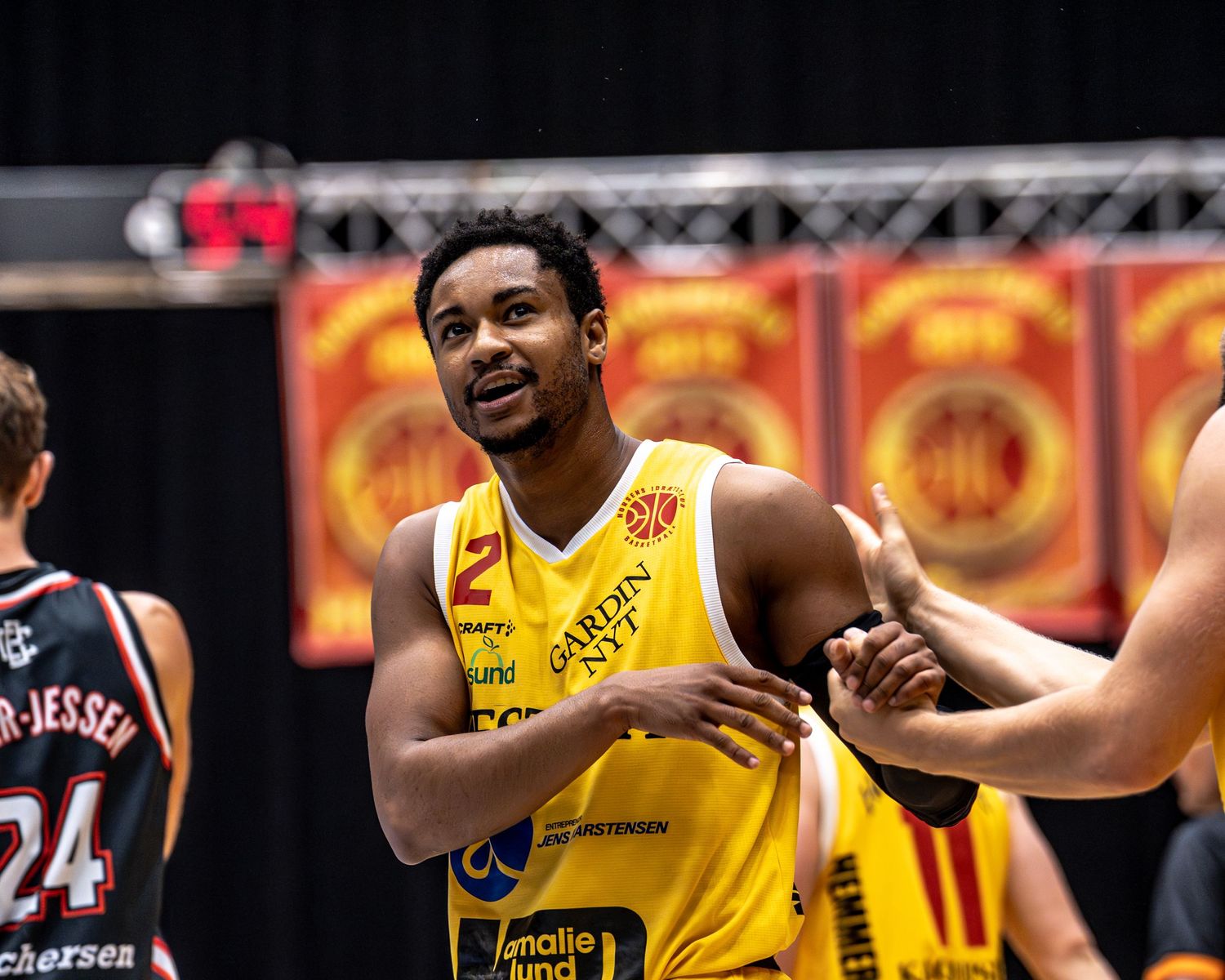 Basketball player number 2 in yellow jersey smiling during game break.