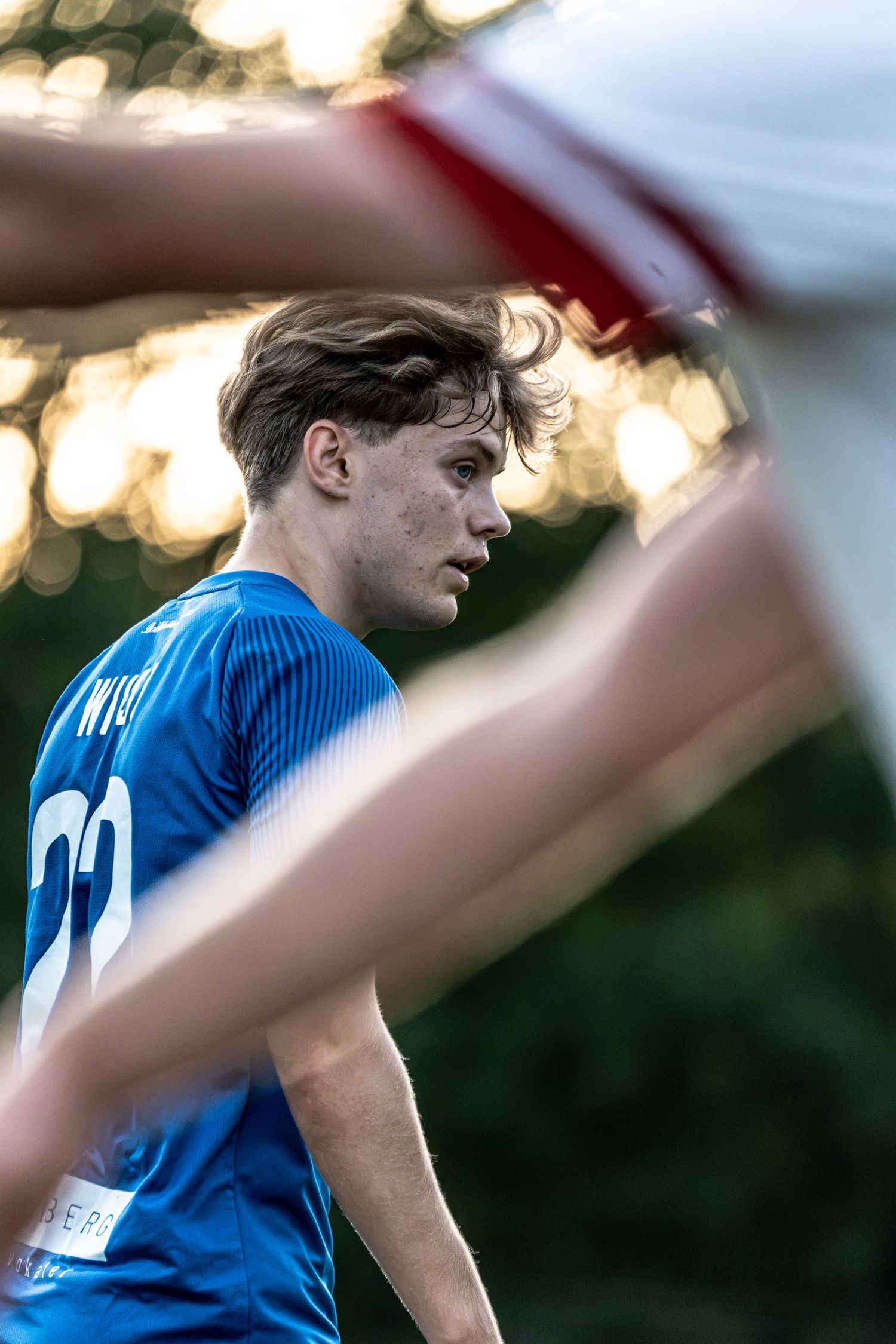 Young soccer player in blue jersey number 22 focuses intently during a football match.