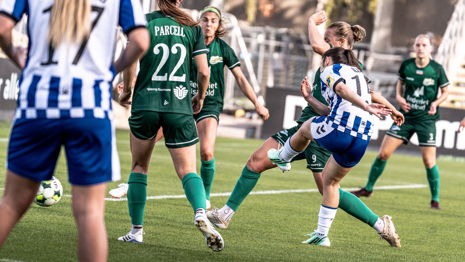 Player #17 Ibgaard in blue and white IFK jersey adjusts her ponytail during a women's football match.
