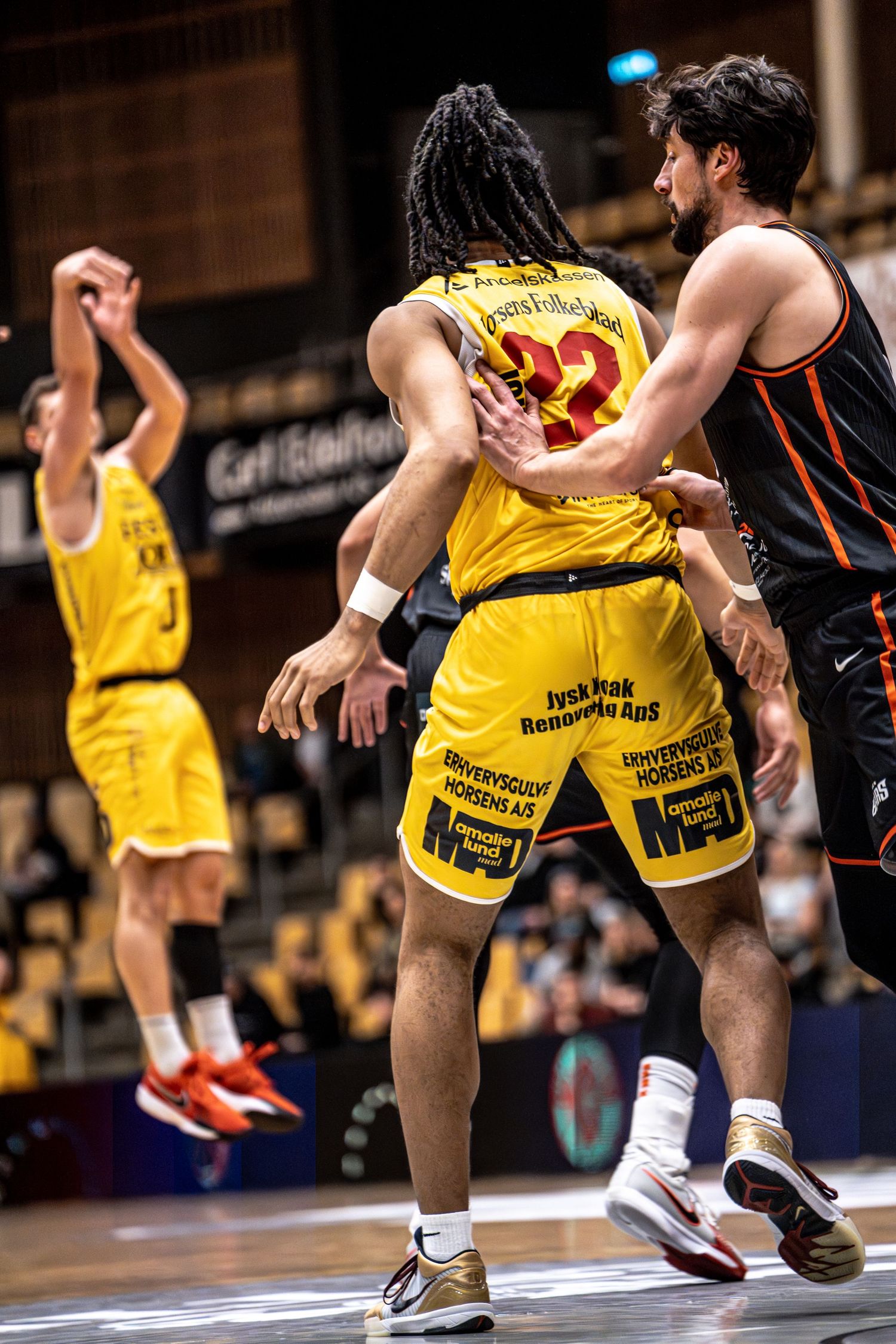 Player number 22 in yellow jersey battles for position against a black-uniformed defender.