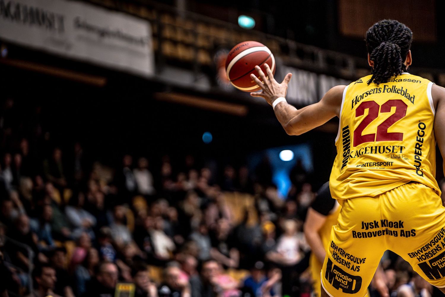 Basketball player number 22 in yellow prepares to shoot in front of packed crowd.