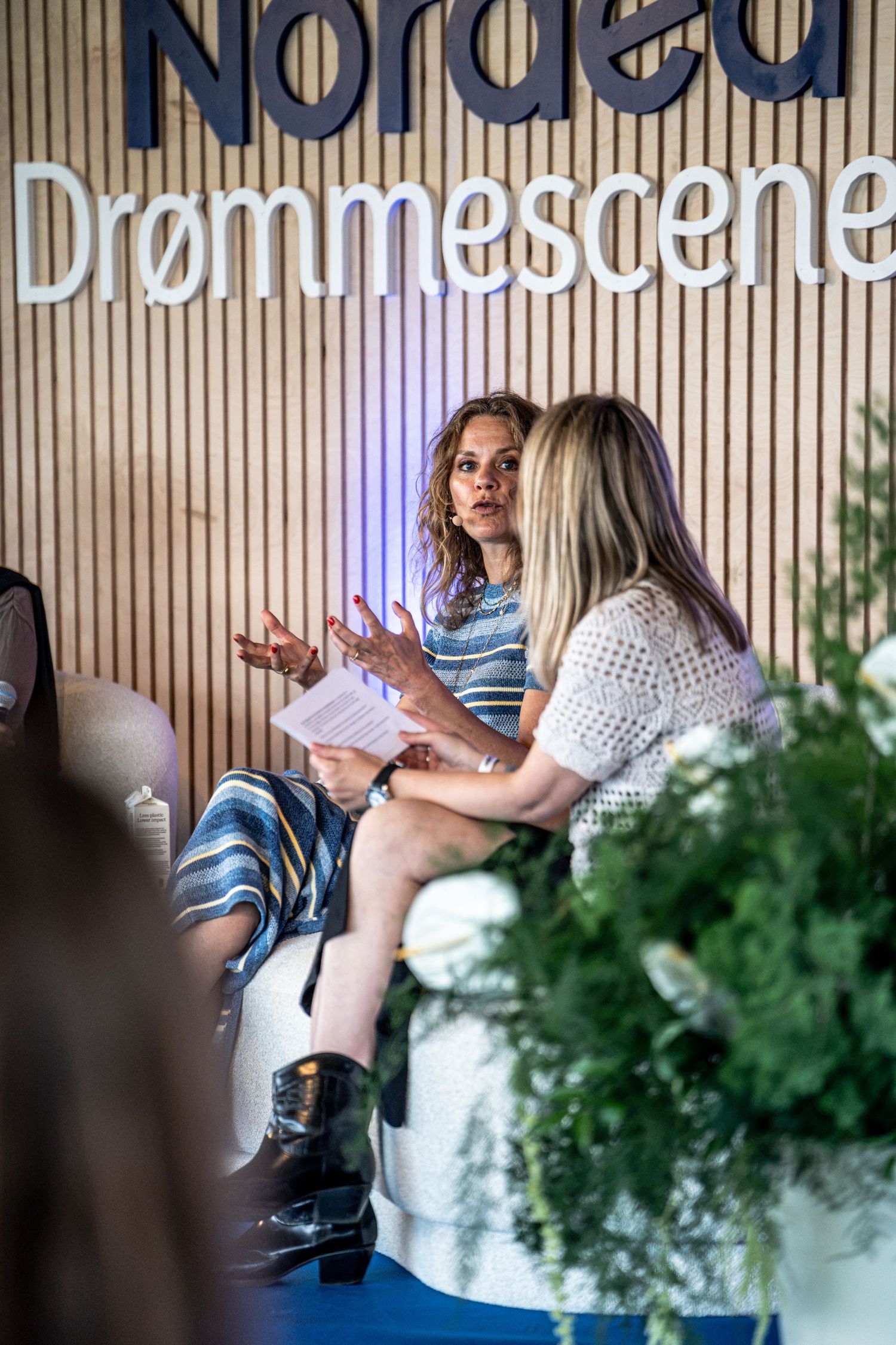 Two women engaged in conversation at Nordea Drømmescene indoor panel discussion event.