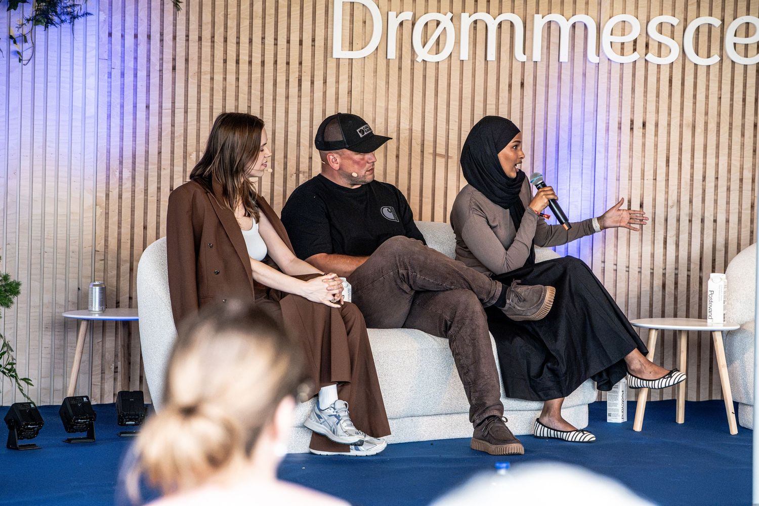 Three panelists sitting on a white sofa on the Drømmescene stage during an outdoor festival discussion.