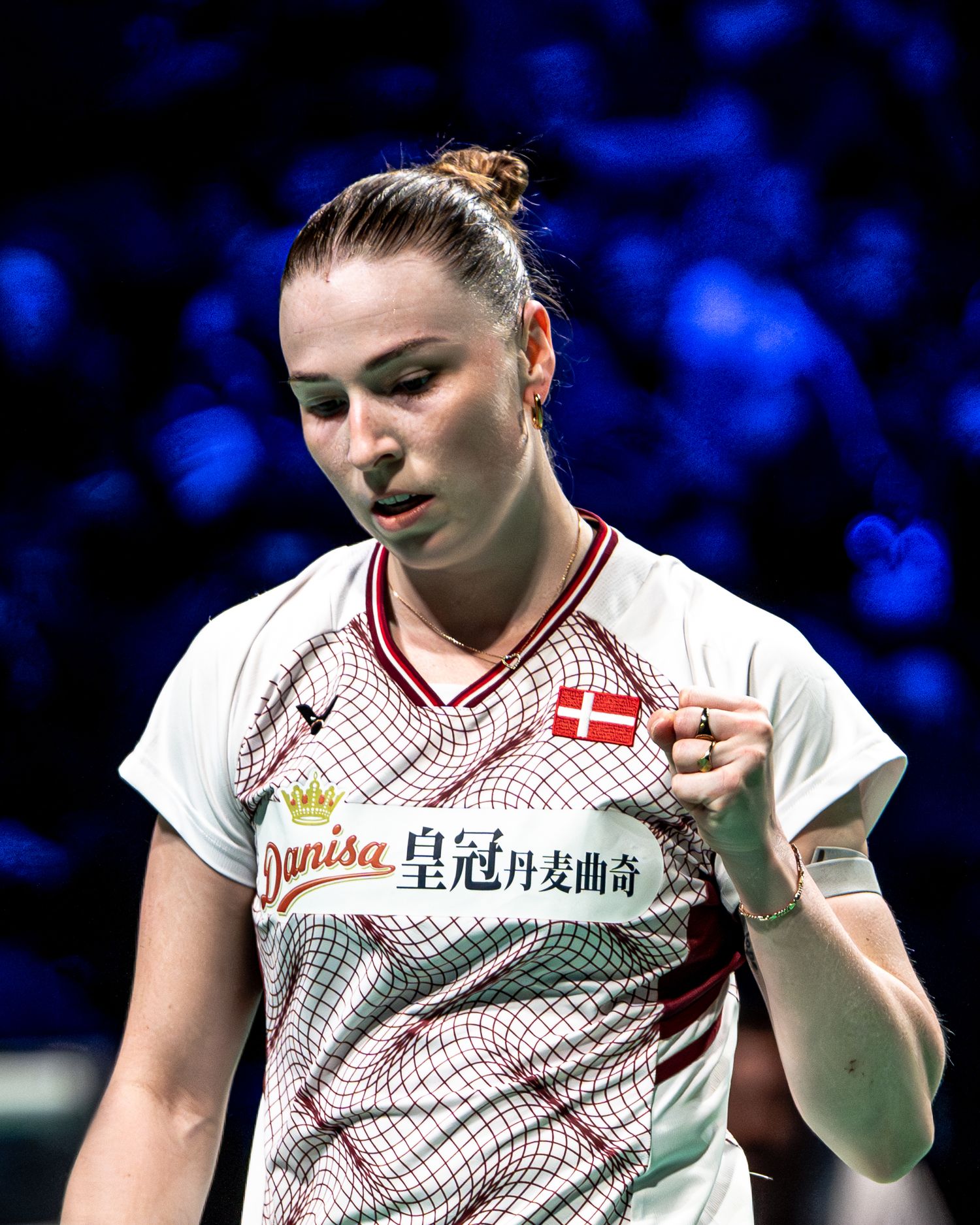 Female Danish badminton player in white jersey celebrating a point during a professional tournament.