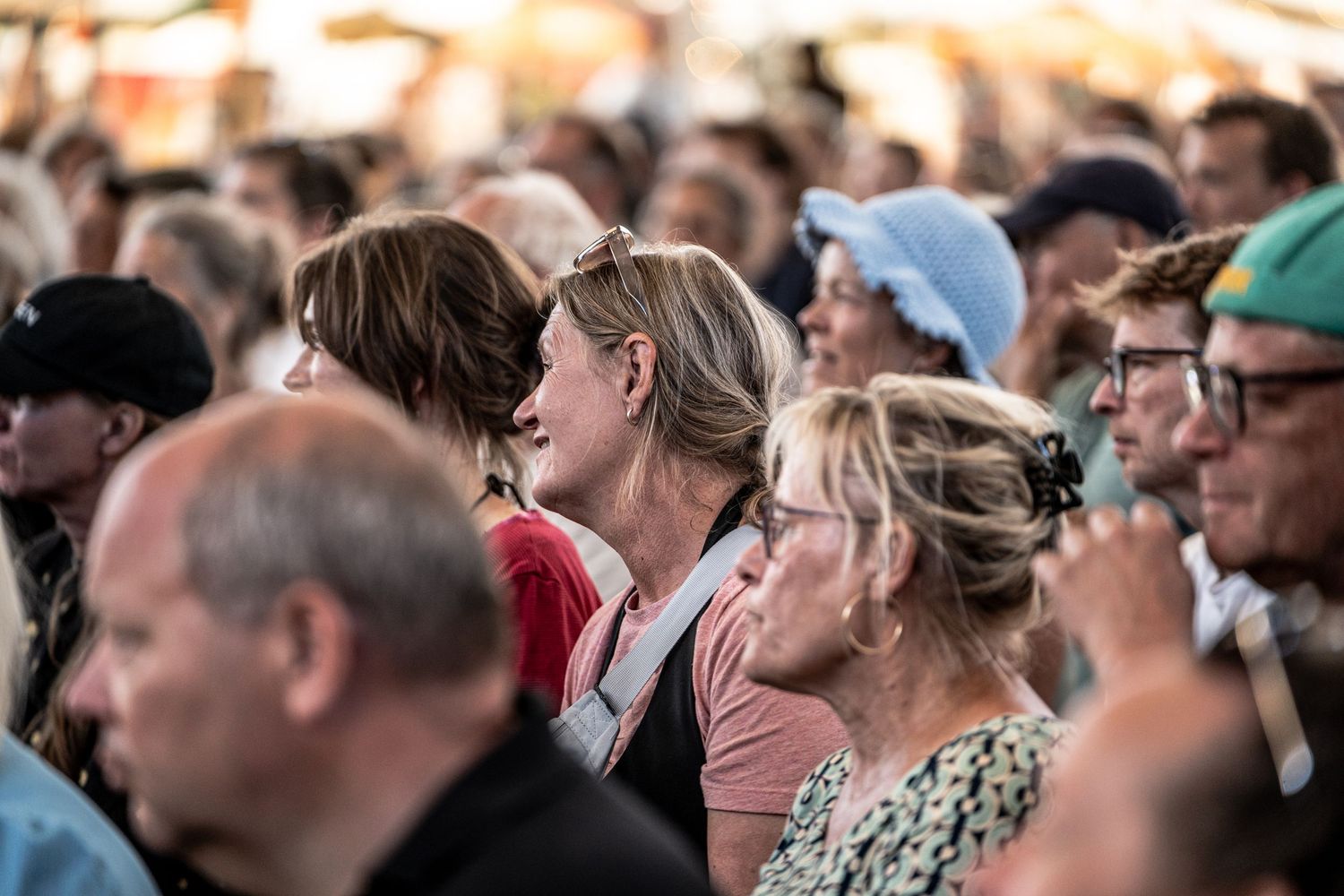 Large crowd of attentive audience members gathered at an outdoor summer festival event.