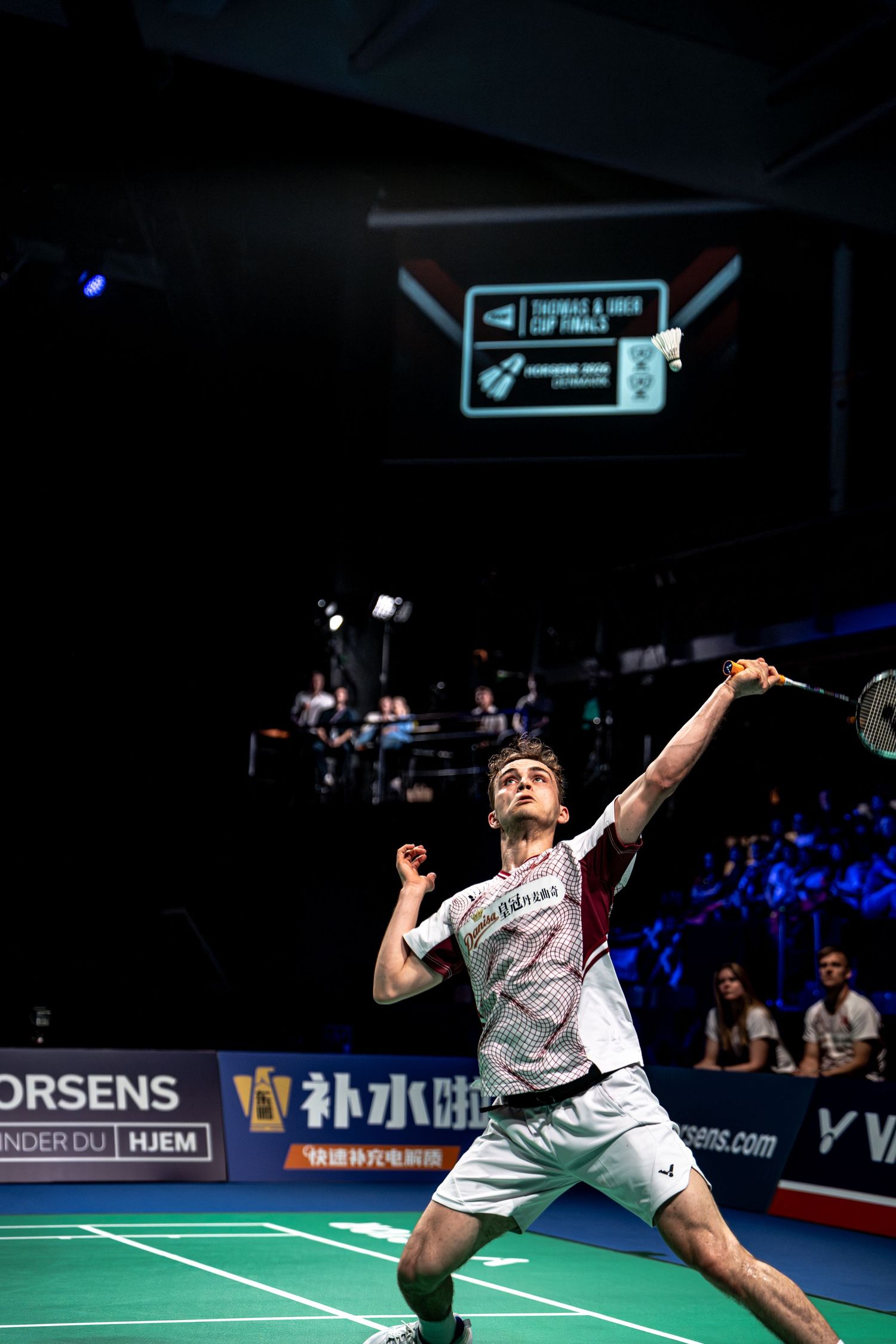 Male badminton player leaping to hit overhead shot during Thomas and Uber Cup Finals tournament in Horsens.