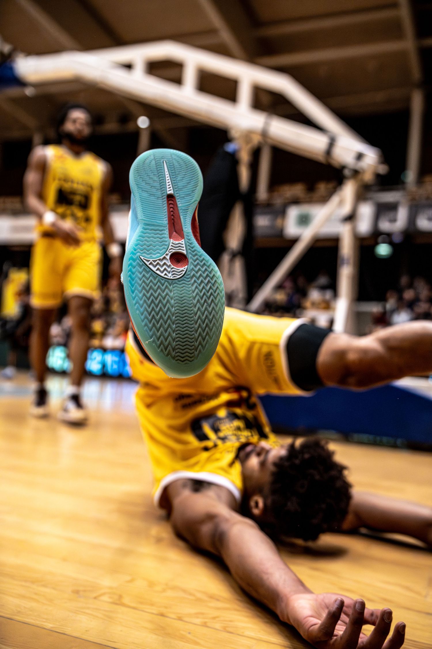 A basketball player falls on the court showing Nike shoe sole during a professional game.