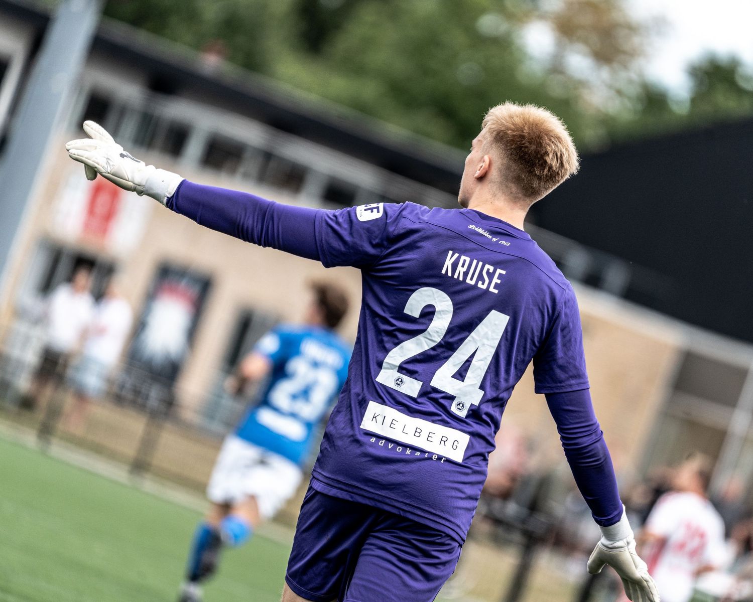 Soccer goalkeeper Kruse wearing number 24 purple jersey gestures on the field during a match.