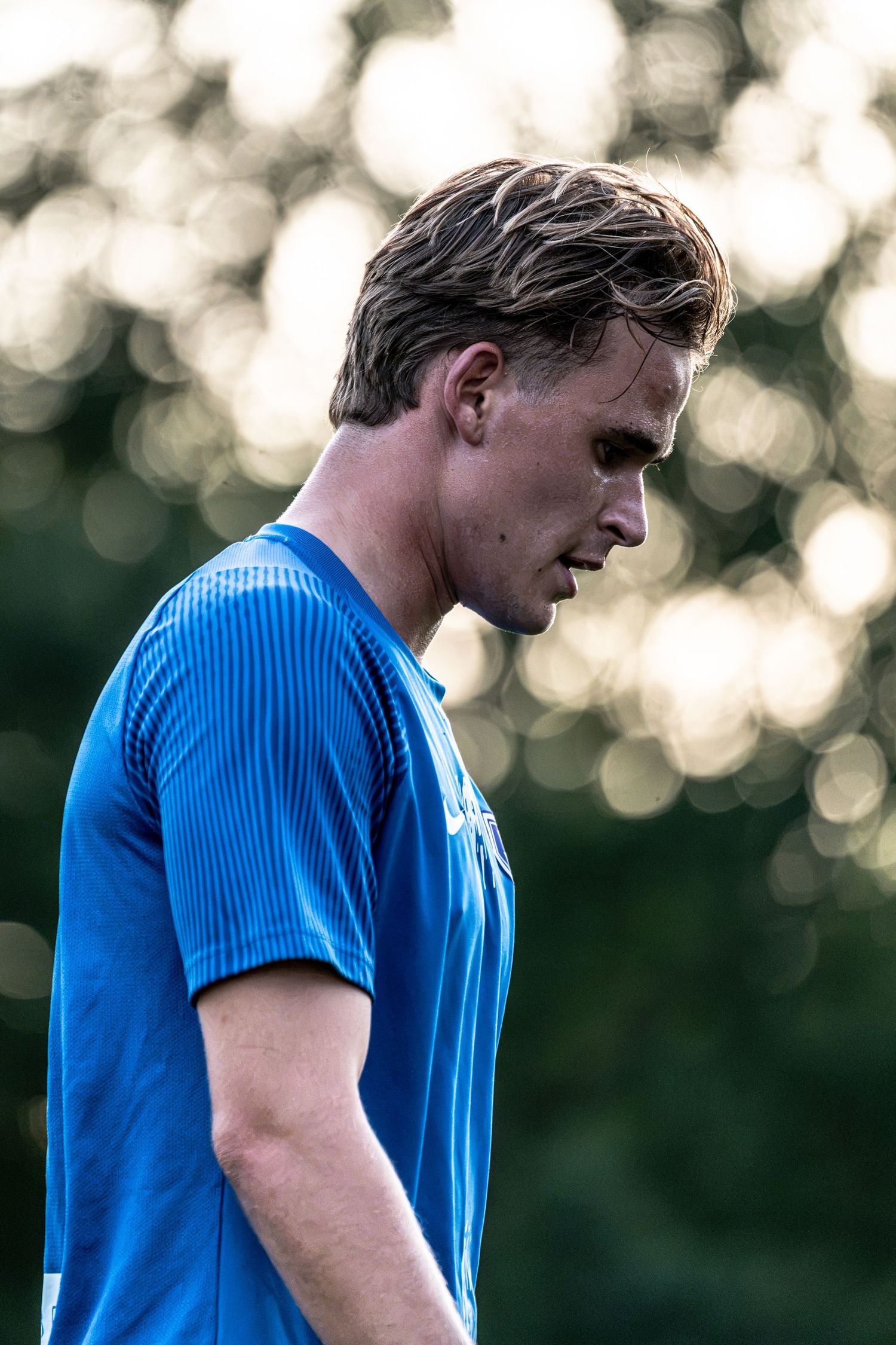 Close-up portrait of a young male soccer player in a blue jersey with bokeh background.