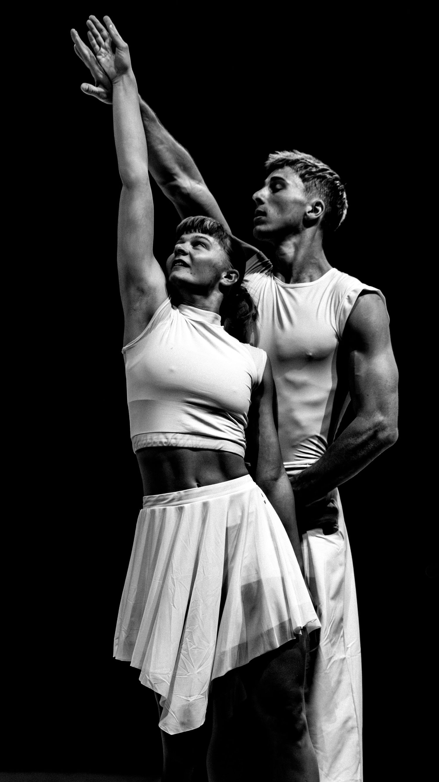 Black and white photo of two contemporary dancers in white performing a dramatic duet.