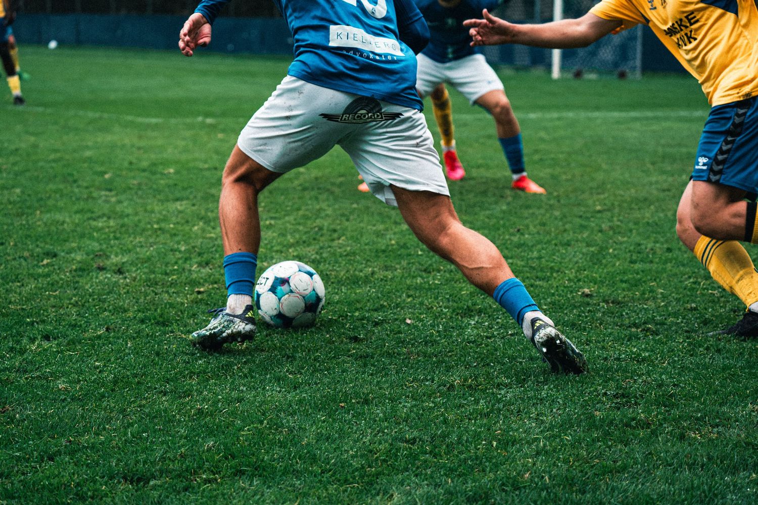Close-up of soccer players competing for the ball during a match on green grass.