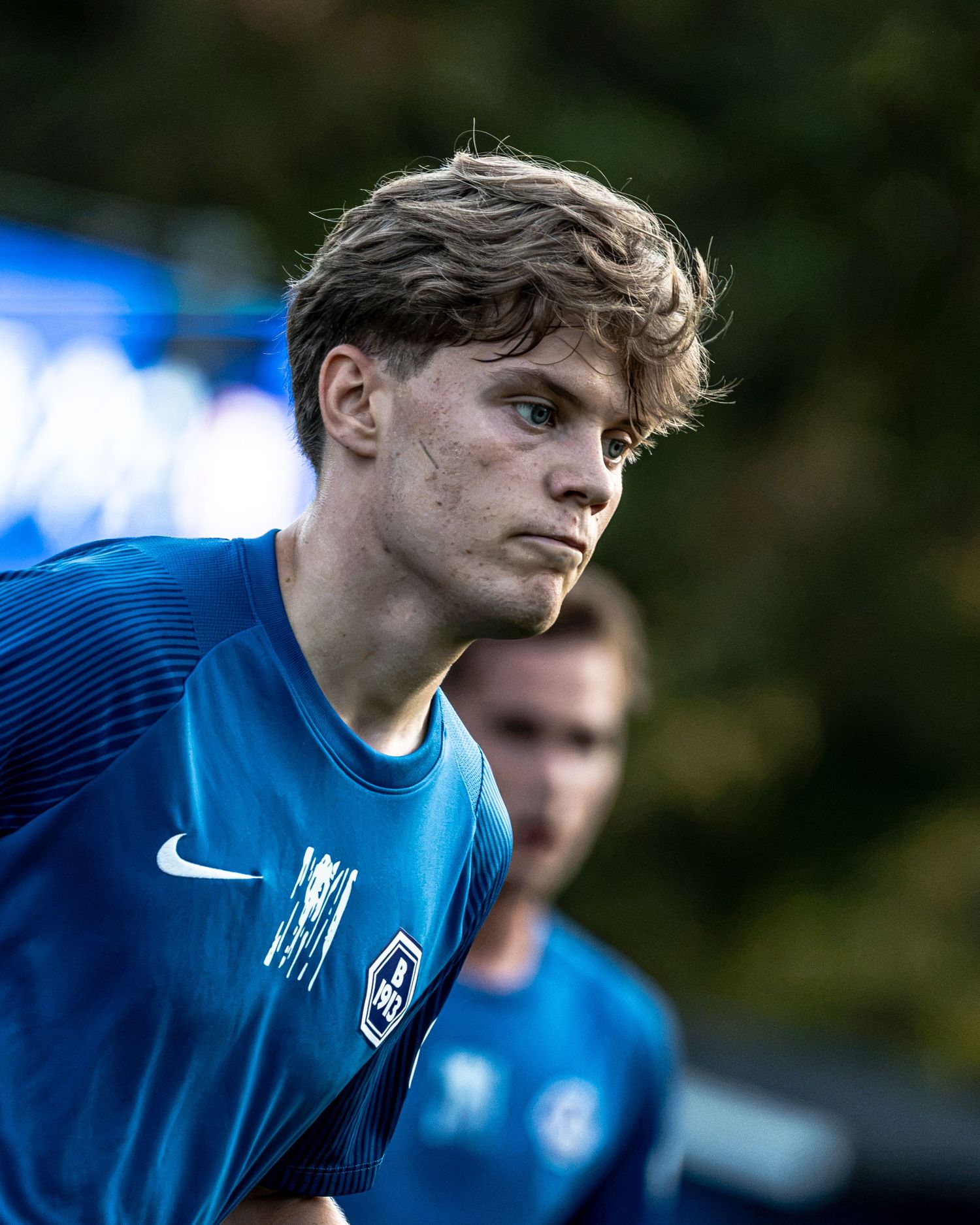 Young male soccer player in blue kit with Nike logo, focused expression during training session.