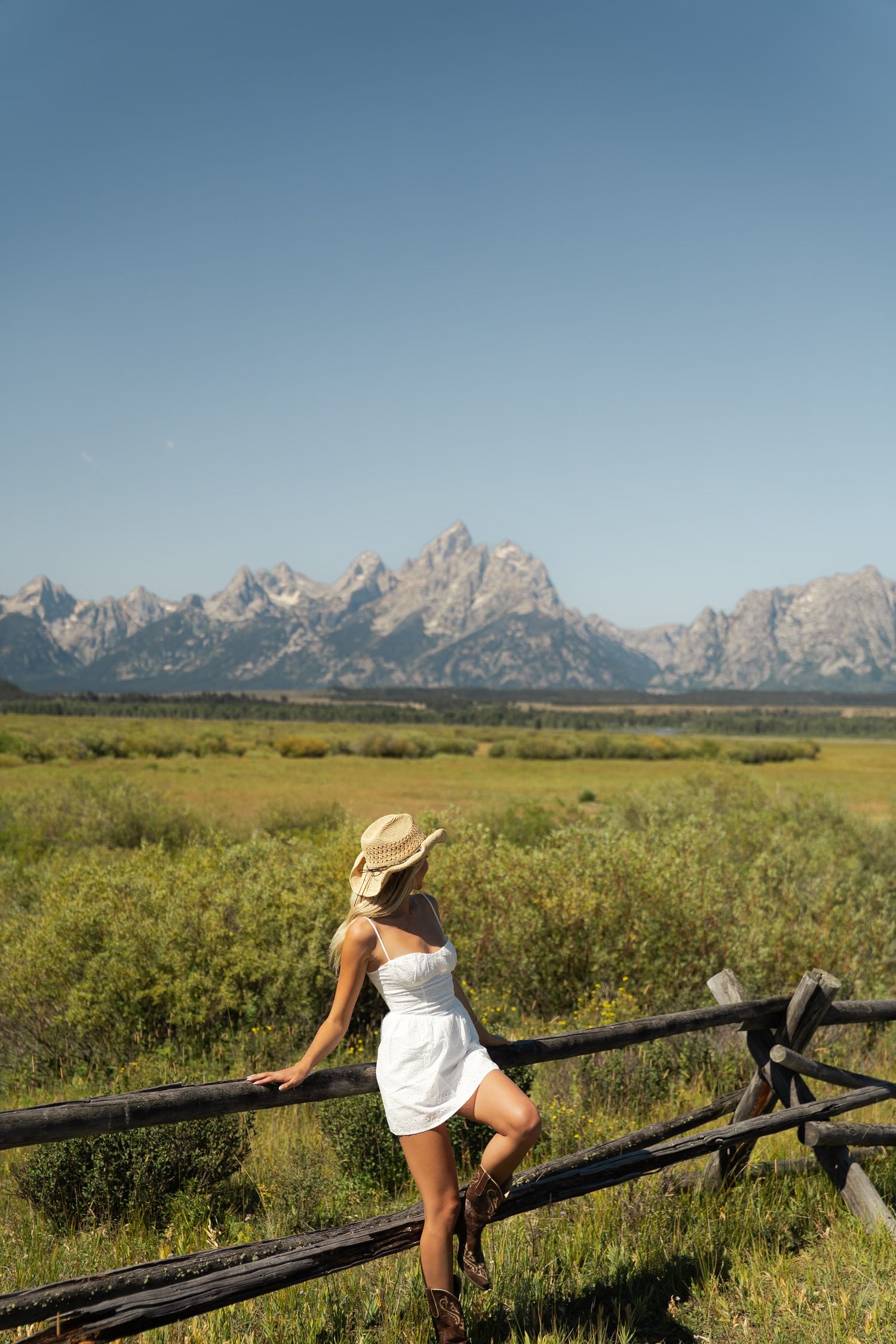 a girl in the mountains wearing a cowboy hat looking awya