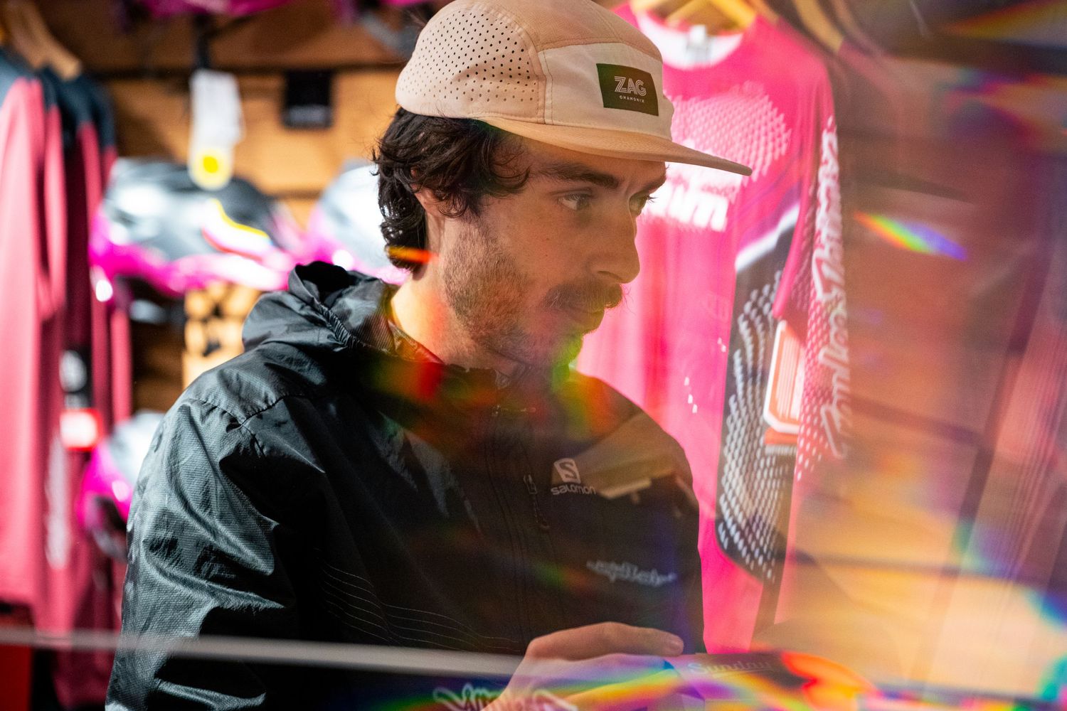 Young man in a cap examining colorful merchandise through a prismatic lens effect.