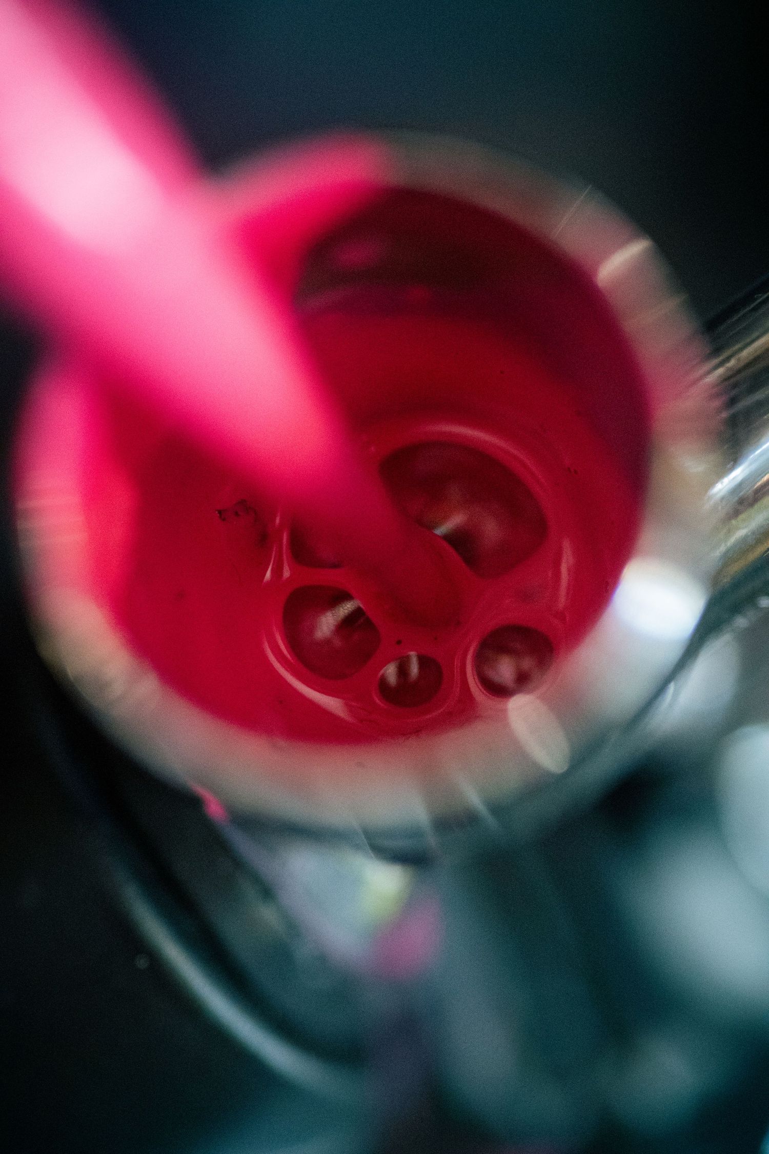 Close-up aerial view of a vibrant red cocktail in a martini glass with a pink straw.