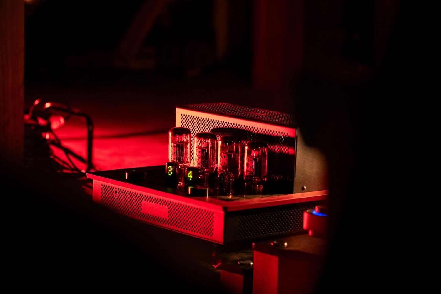 Glowing red vacuum tube amplifier on a dark surface, emitting warm red light from vintage audio equipment.