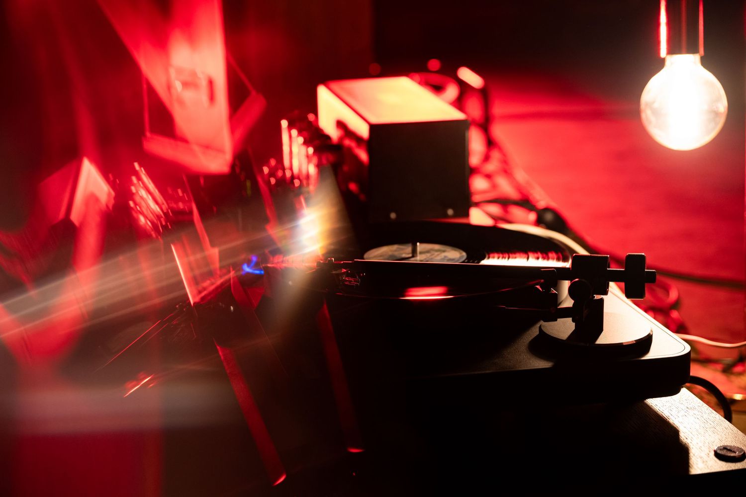 Vinyl record spinning on a turntable with red ambient club lighting and light beams.