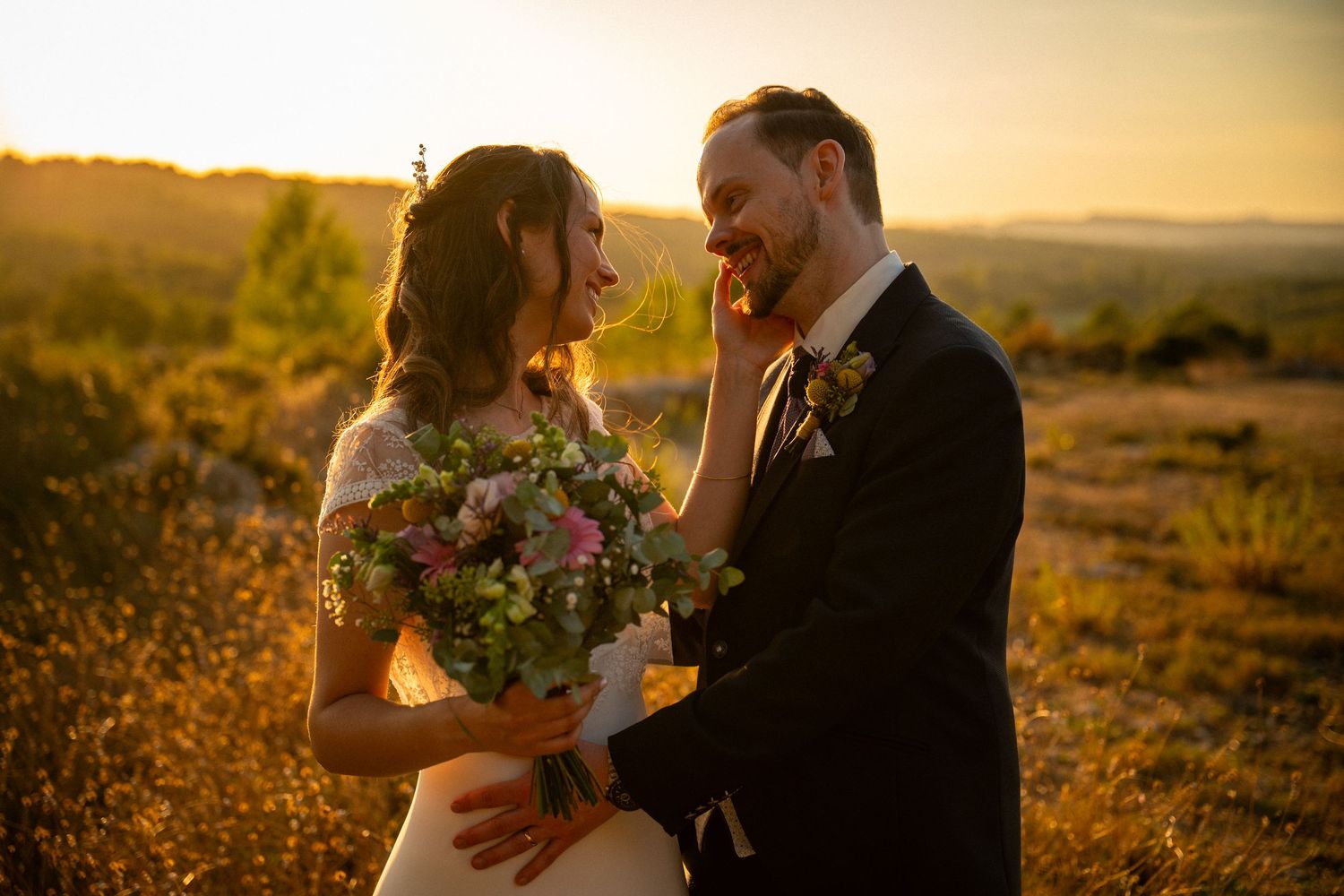 Bride and groom sharing a romantic golden hour moment in a sun-drenched field with bouquet.