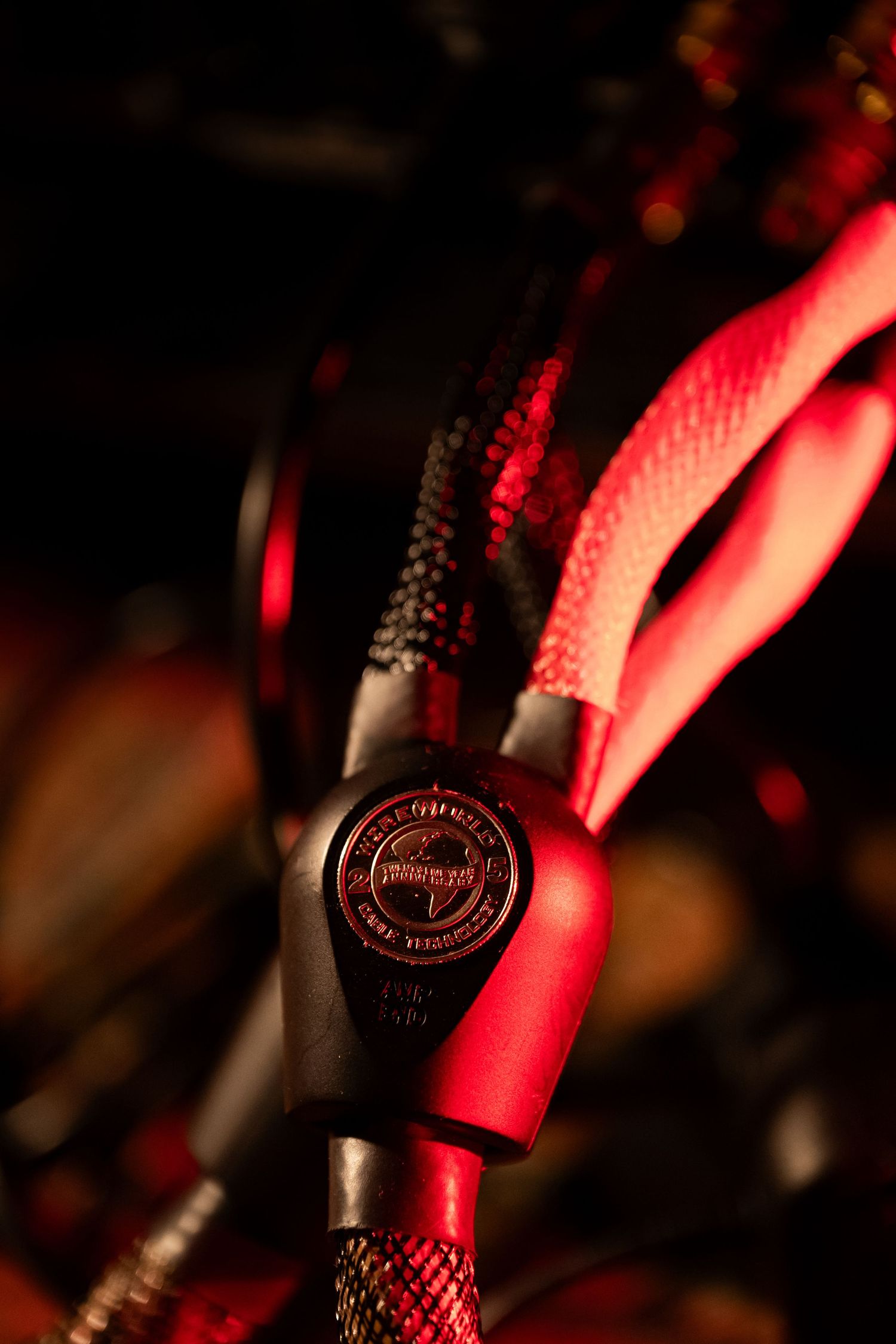 Close-up of red and black braided cable with a branded cord lock connector on dark background.