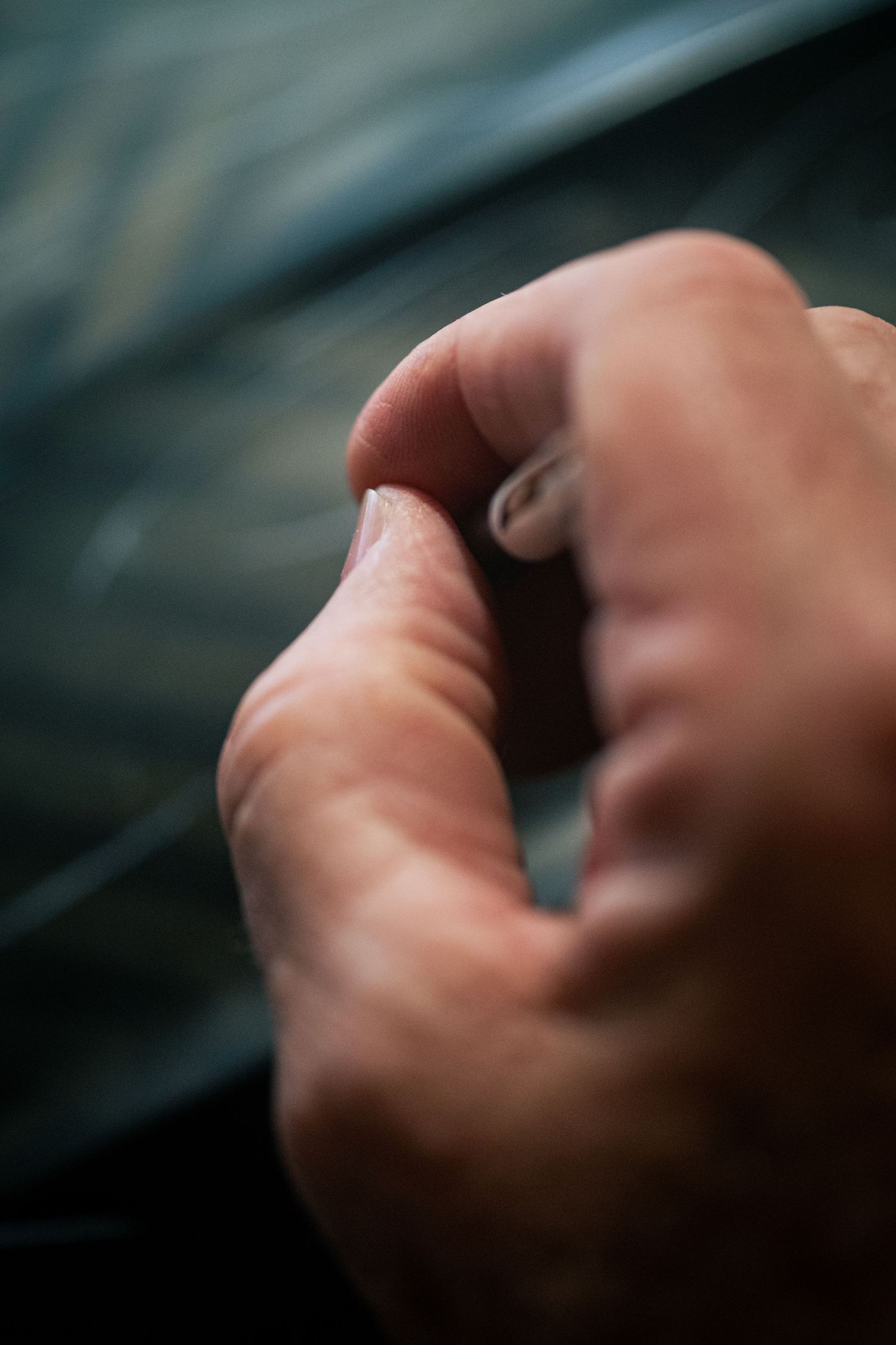 Close-up macro photo of a human hand forming a fist against a dark blurred background.