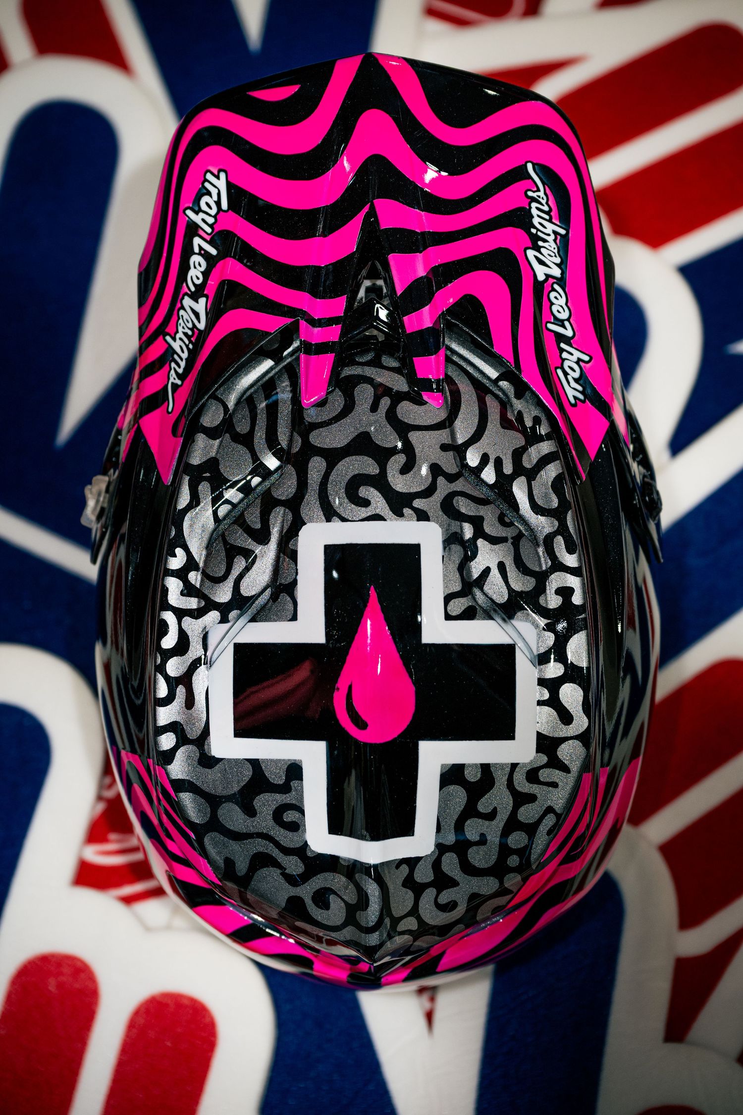 Troy Lee Designs pink and black motocross helmet with Muc-Off logo, viewed from above.
