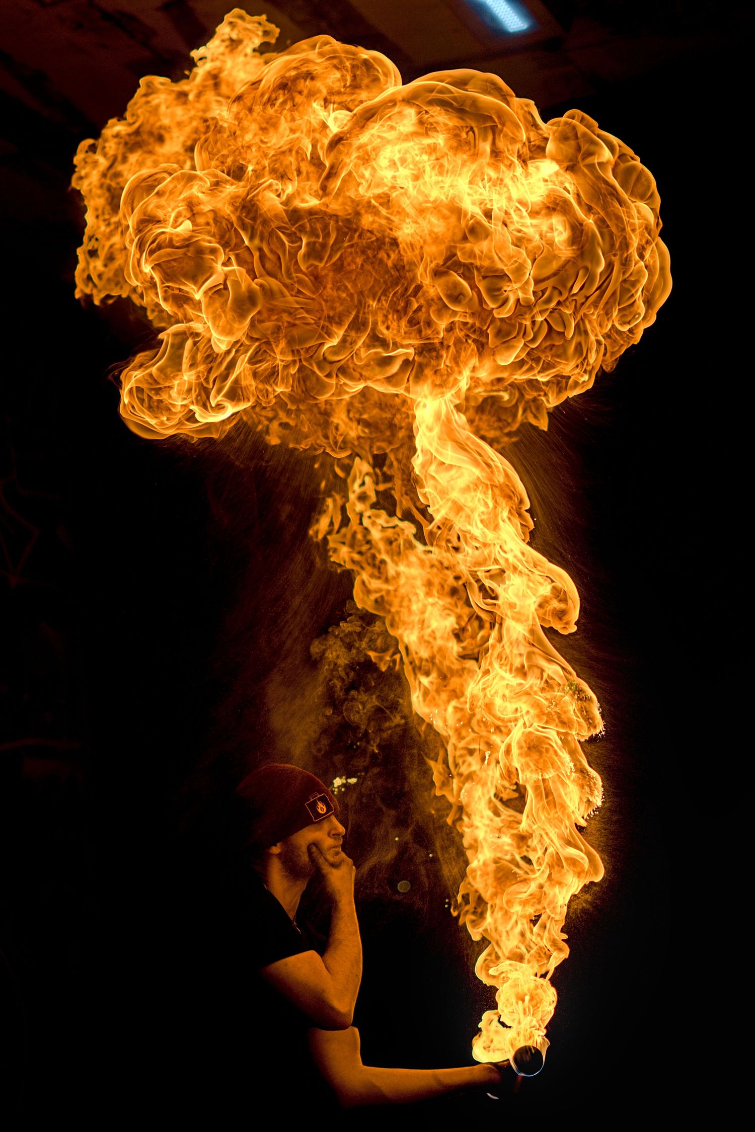 Fire breather exhaling a large mushroom-shaped fireball against a black background.
