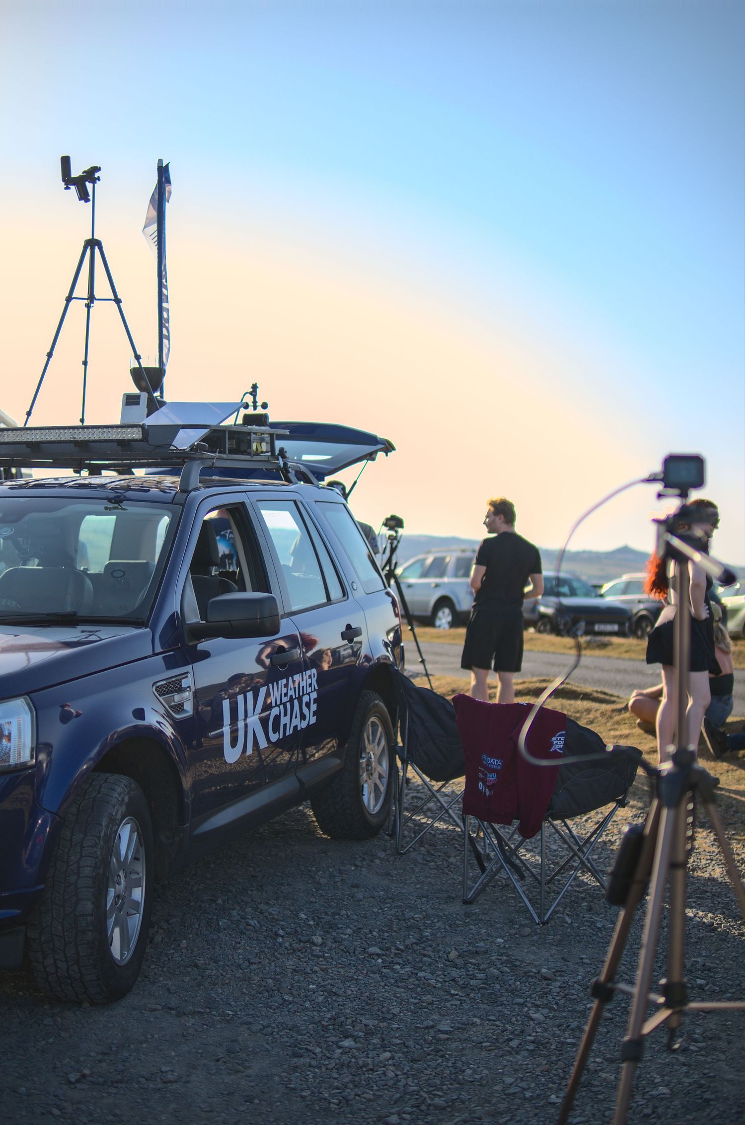 UK Weather Chase vehicle with roof-mounted instruments and camera tripod set up at dusk.