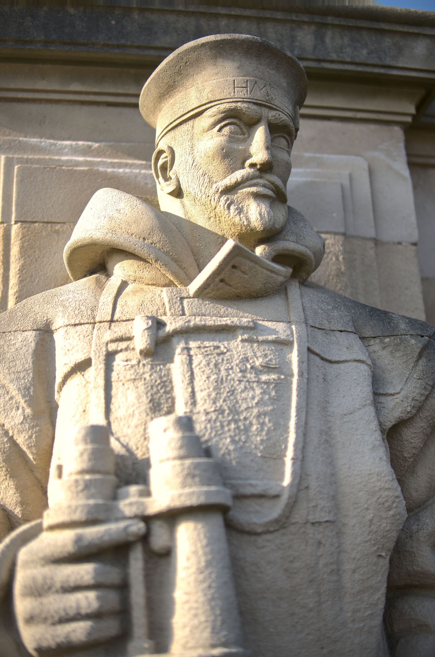Detailed stone sculpture of a bearded military officer holding binoculars on a monument.
