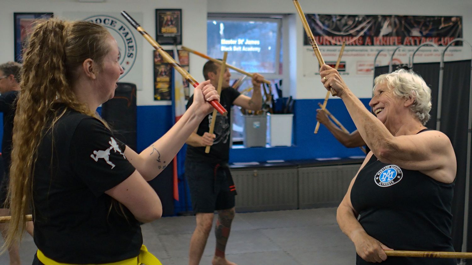 Two women practice Filipino stick fighting techniques at a martial arts school.