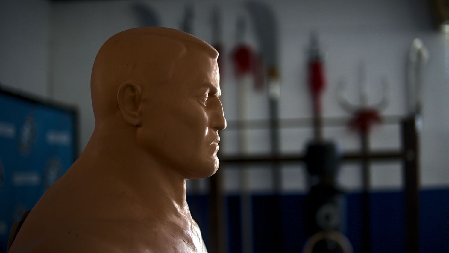 A realistic training dummy bust used for martial arts practice in a gym.
